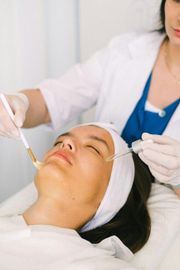Esthetician applying cosmetic treatment to a woman's face with tools in a spa setting