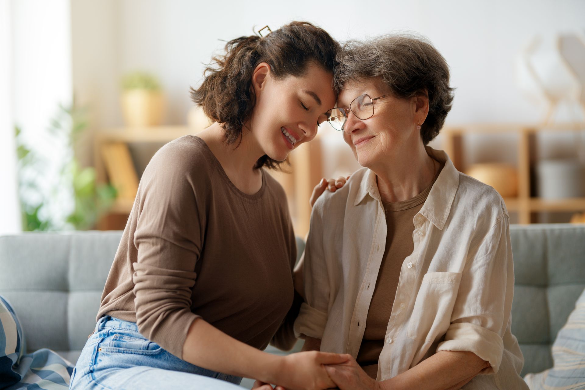 Two people sitting close on a couch, smiling and holding hands in a warm living room.