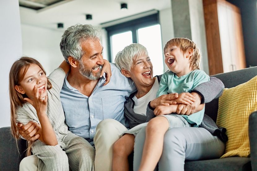 Four people laughing together on a couch in a bright living room