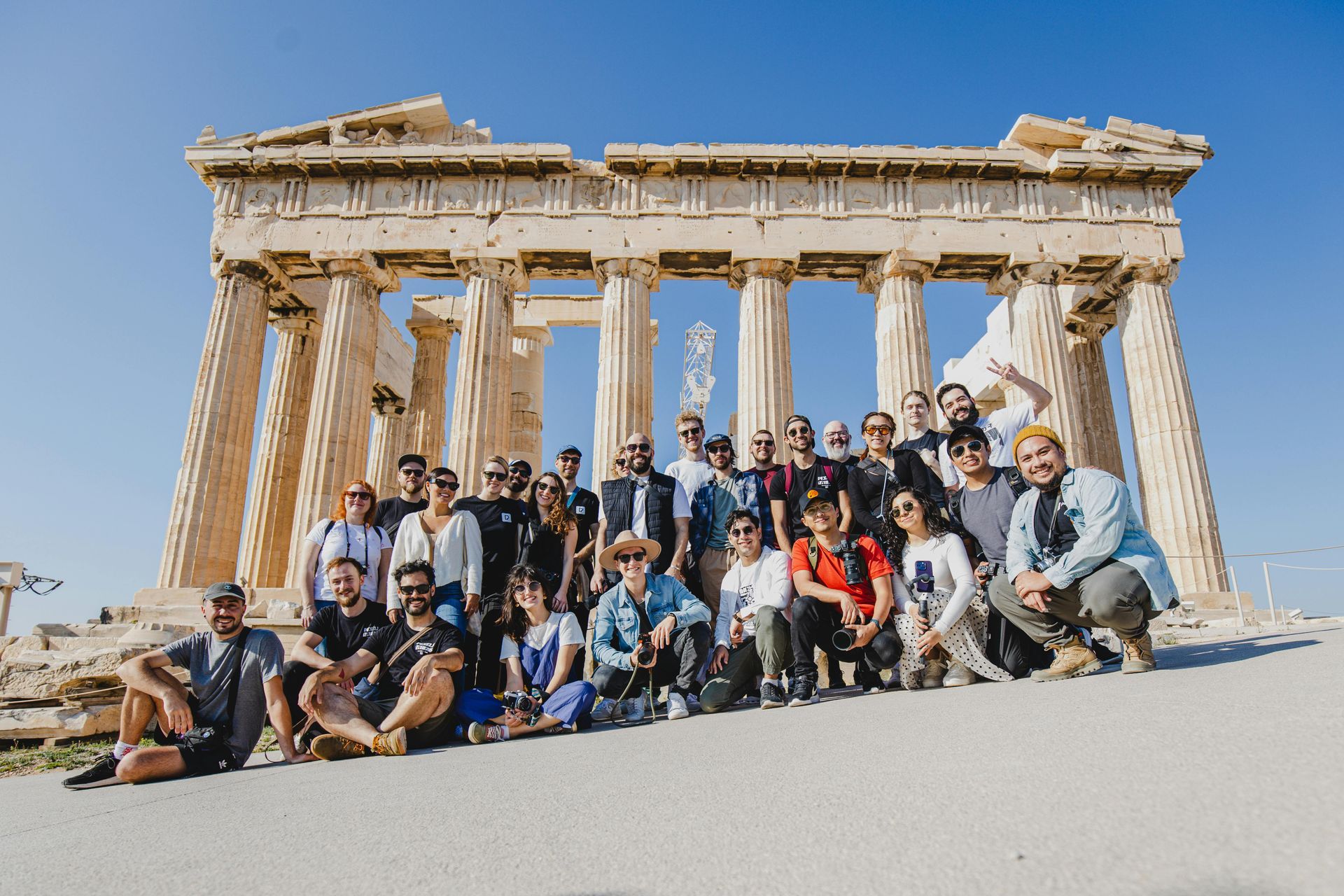 Group posing at the Parthenon ruins on a sunny day, with ancient stone columns in the background
