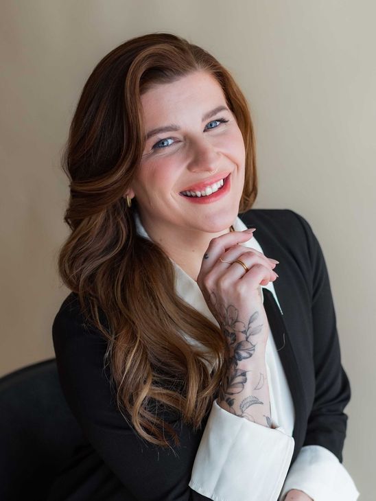 A woman with a tattoo on her arm is smiling for the camera.