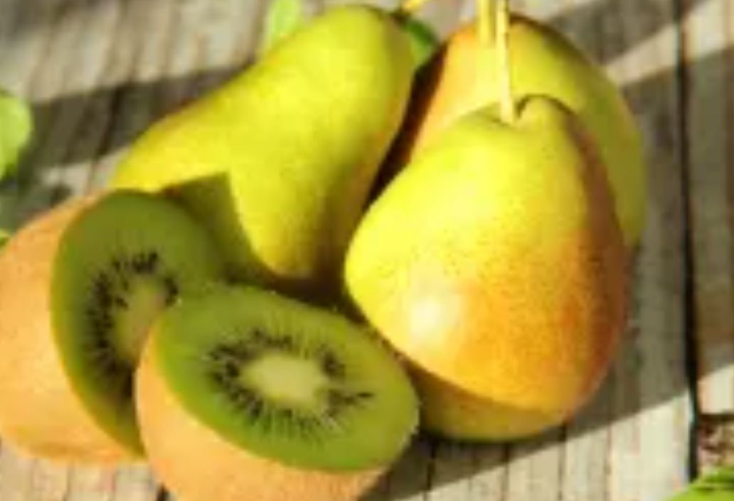 Yellow pears and sliced kiwi on a rustic wooden surface