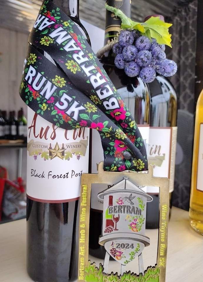 Gift basket with a wine bottle, floral ribbon, purple grapes, and a Bertram gift tag.