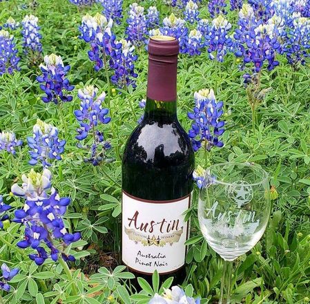 Wine bottle and glass in a field of purple bluebonnets and green grass