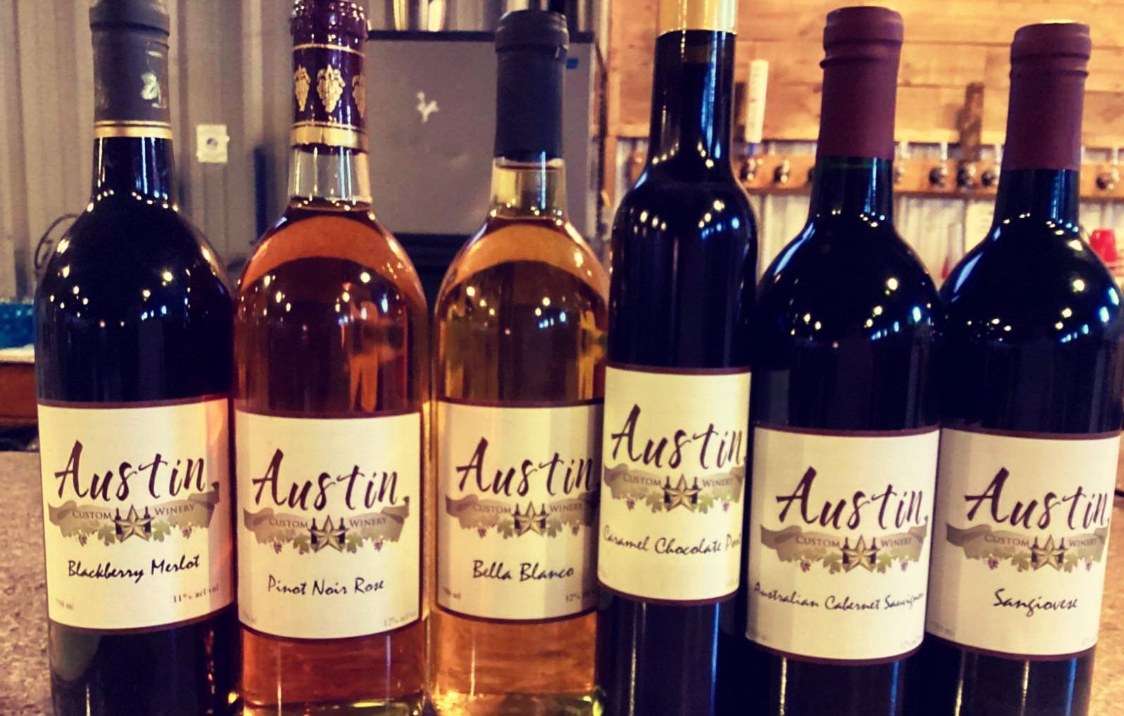 Six Austin wine bottles lined up on a counter, with dark red and amber labels.