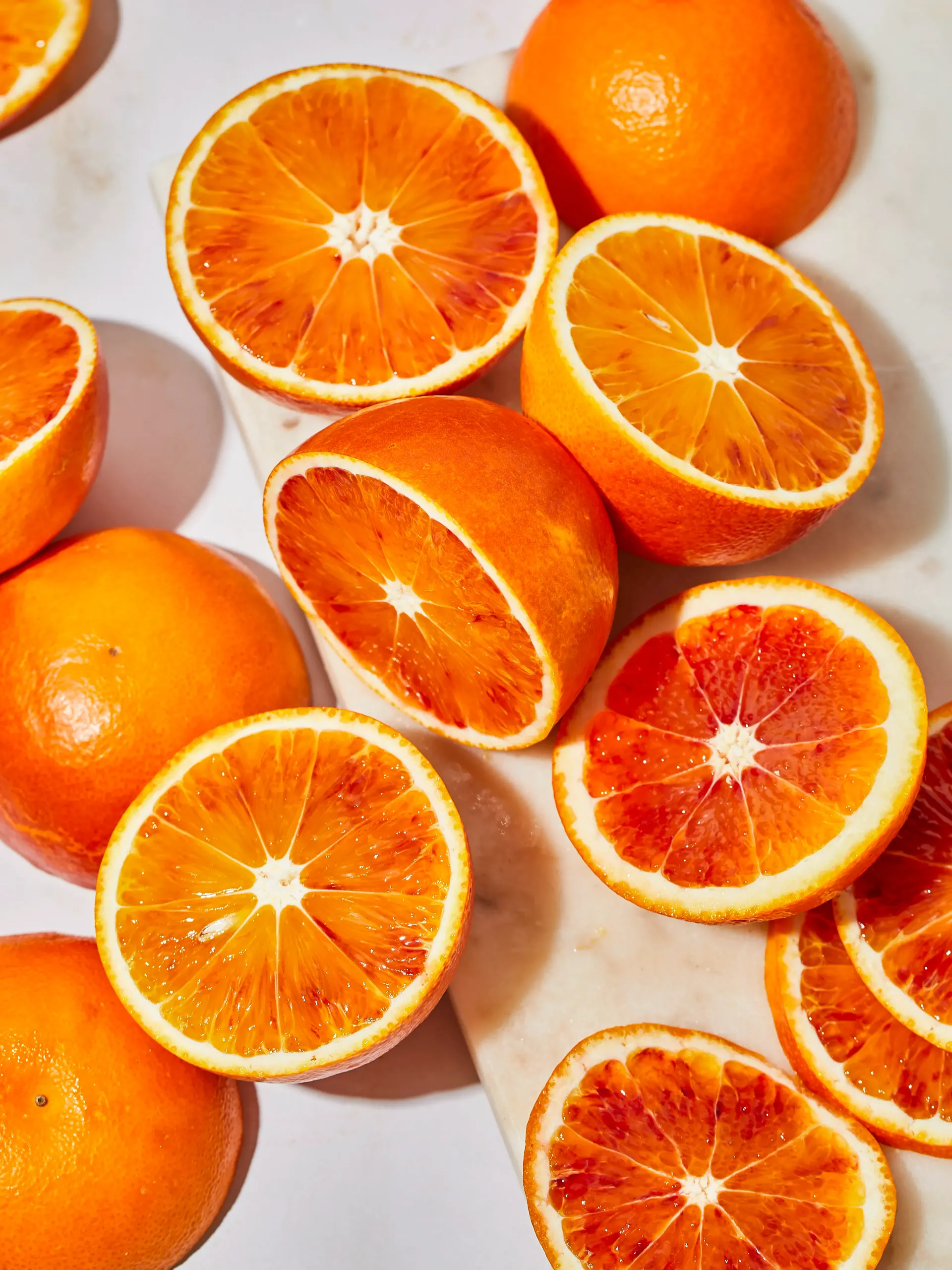 Bright orange halves and whole oranges scattered on a light background