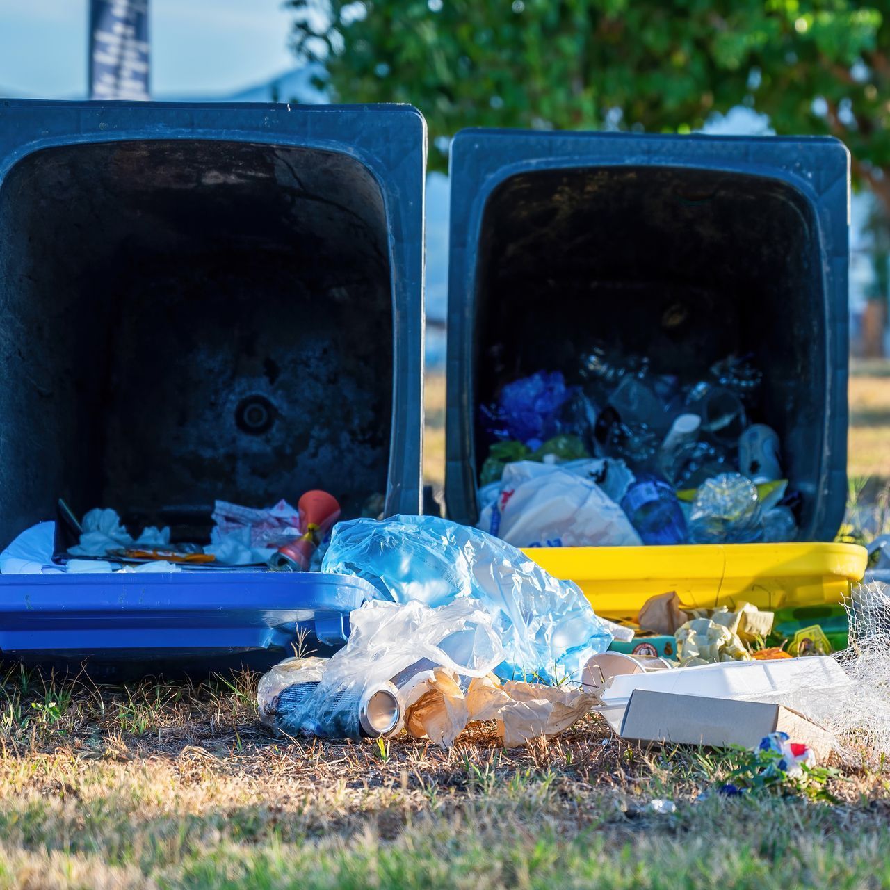 Two trash cans filled with trash are sitting on the ground.