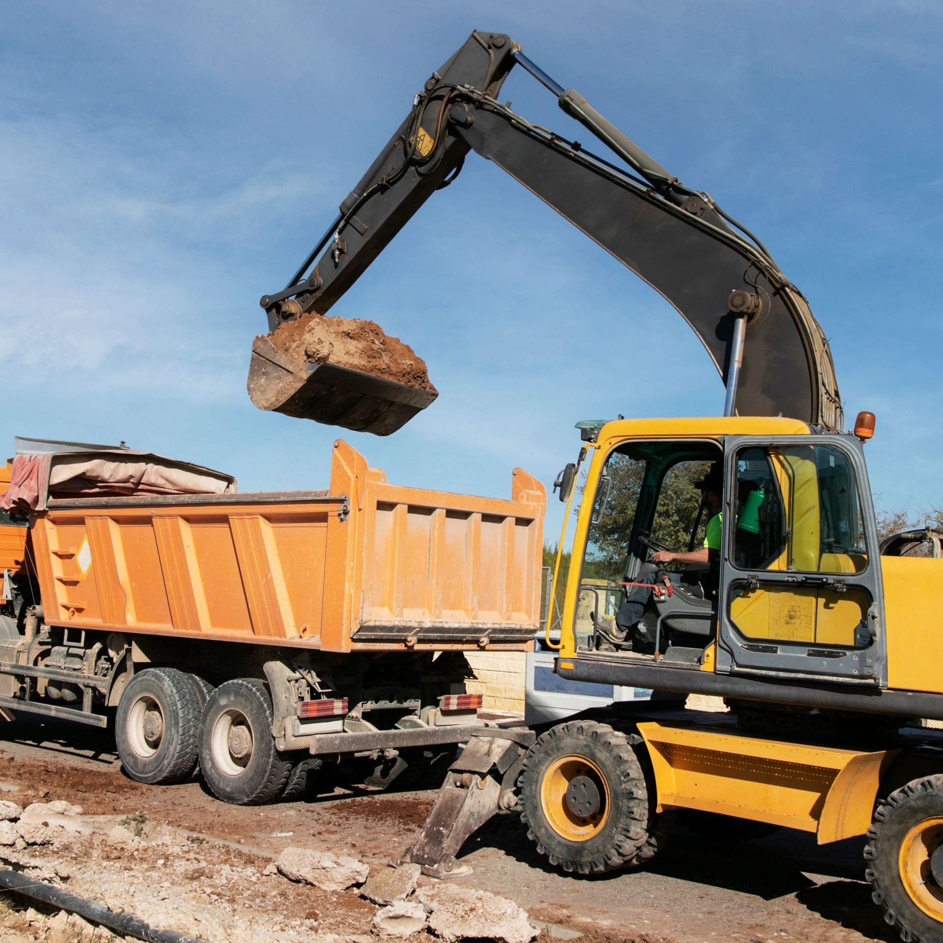 An excavator is loading dirt into a dump truck