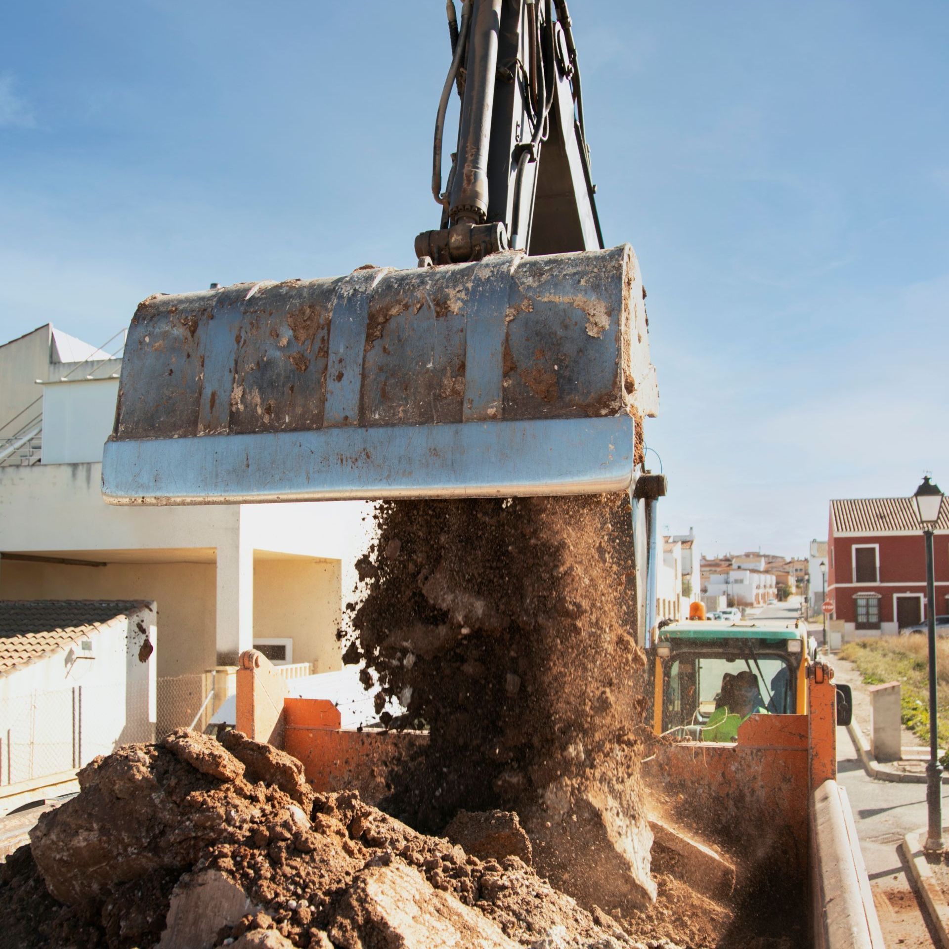 A large bucket of dirt is being poured into a pile