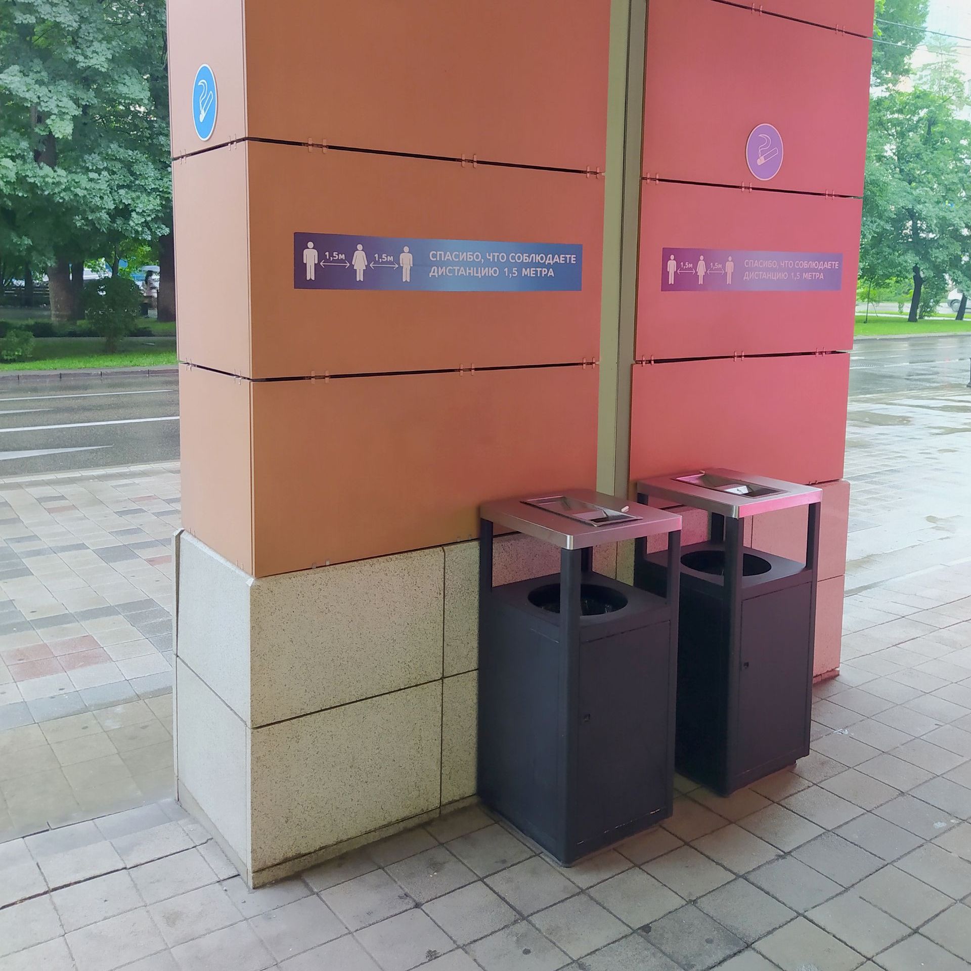 Two trash cans are on the side of a building