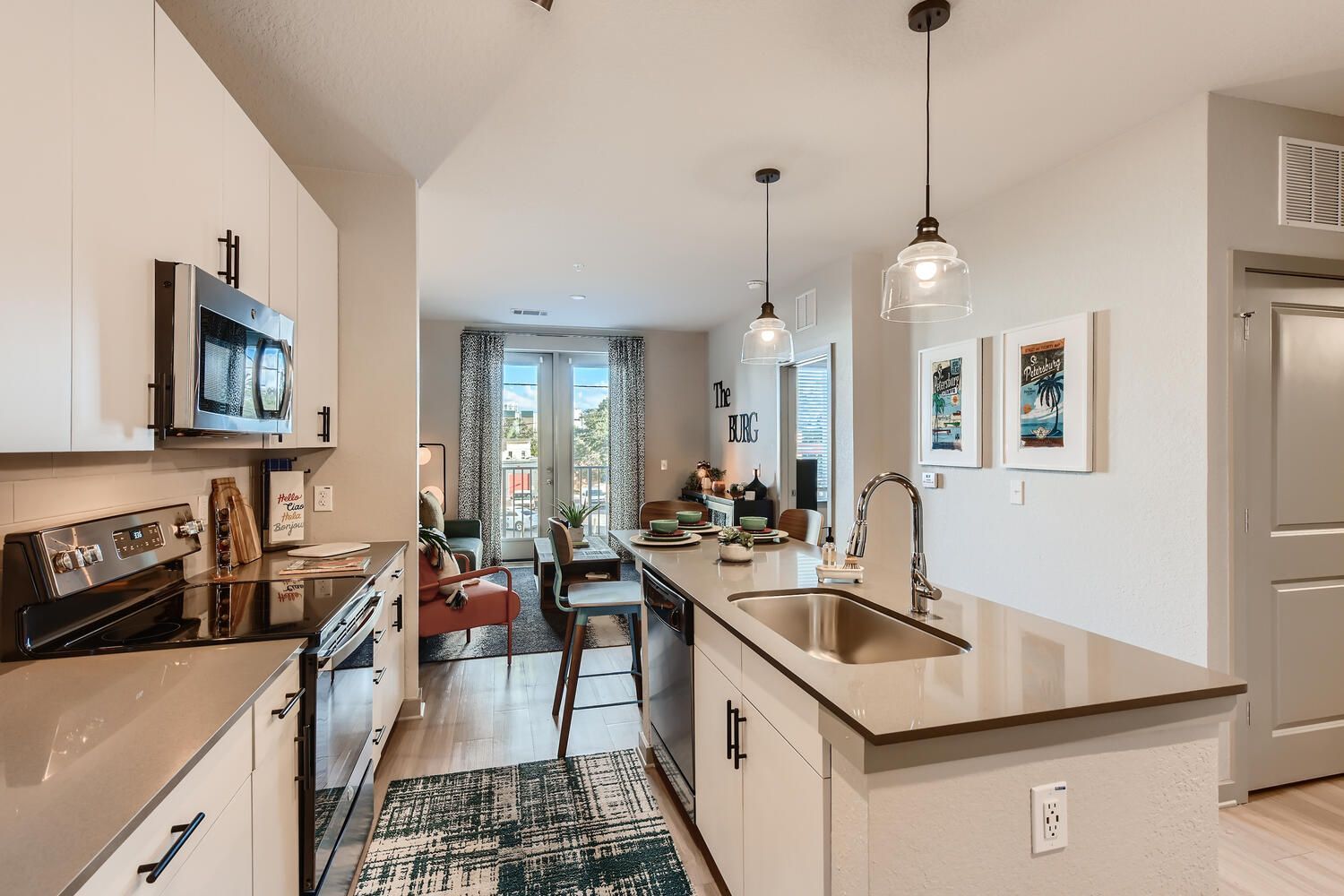 A kitchen with a sink , stove , microwave , and dishwasher.