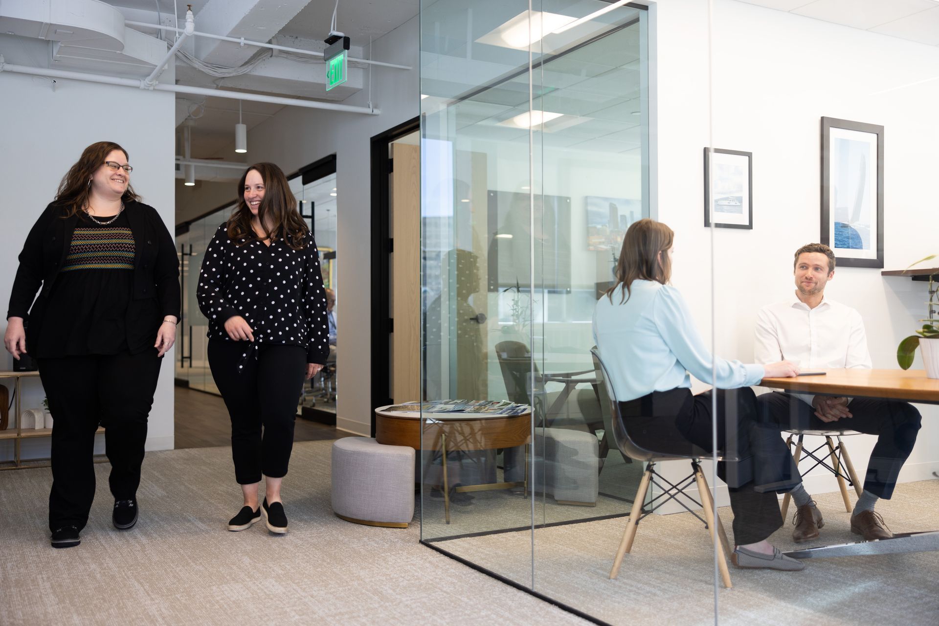 A group of people are walking and sitting at a table in an office.