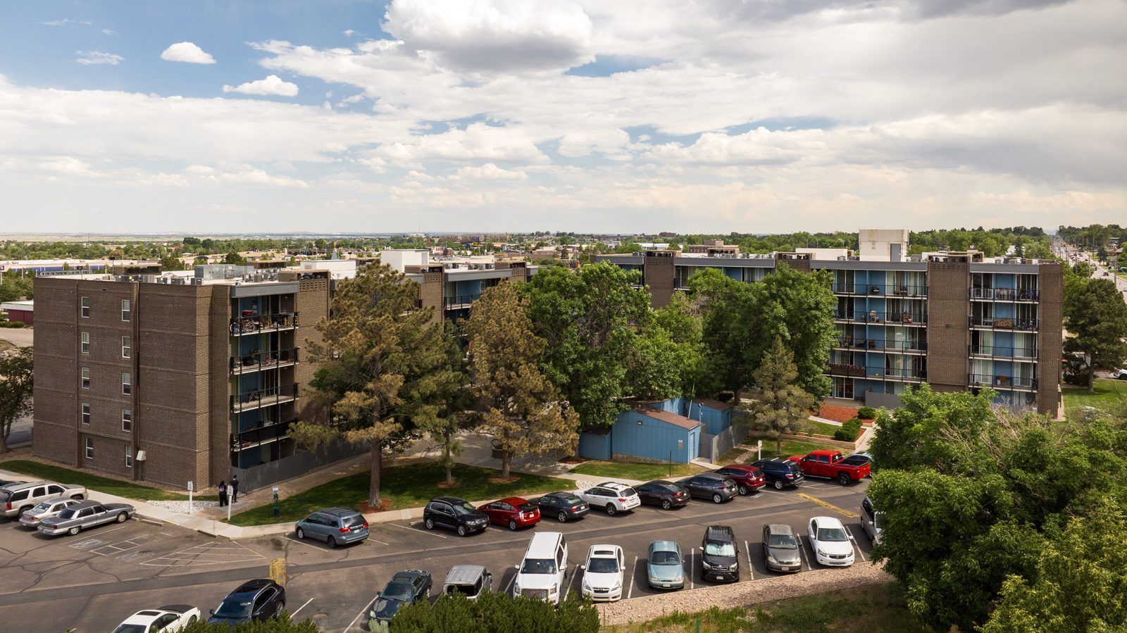 An aerial view of a parking lot with cars parked in front of a building.