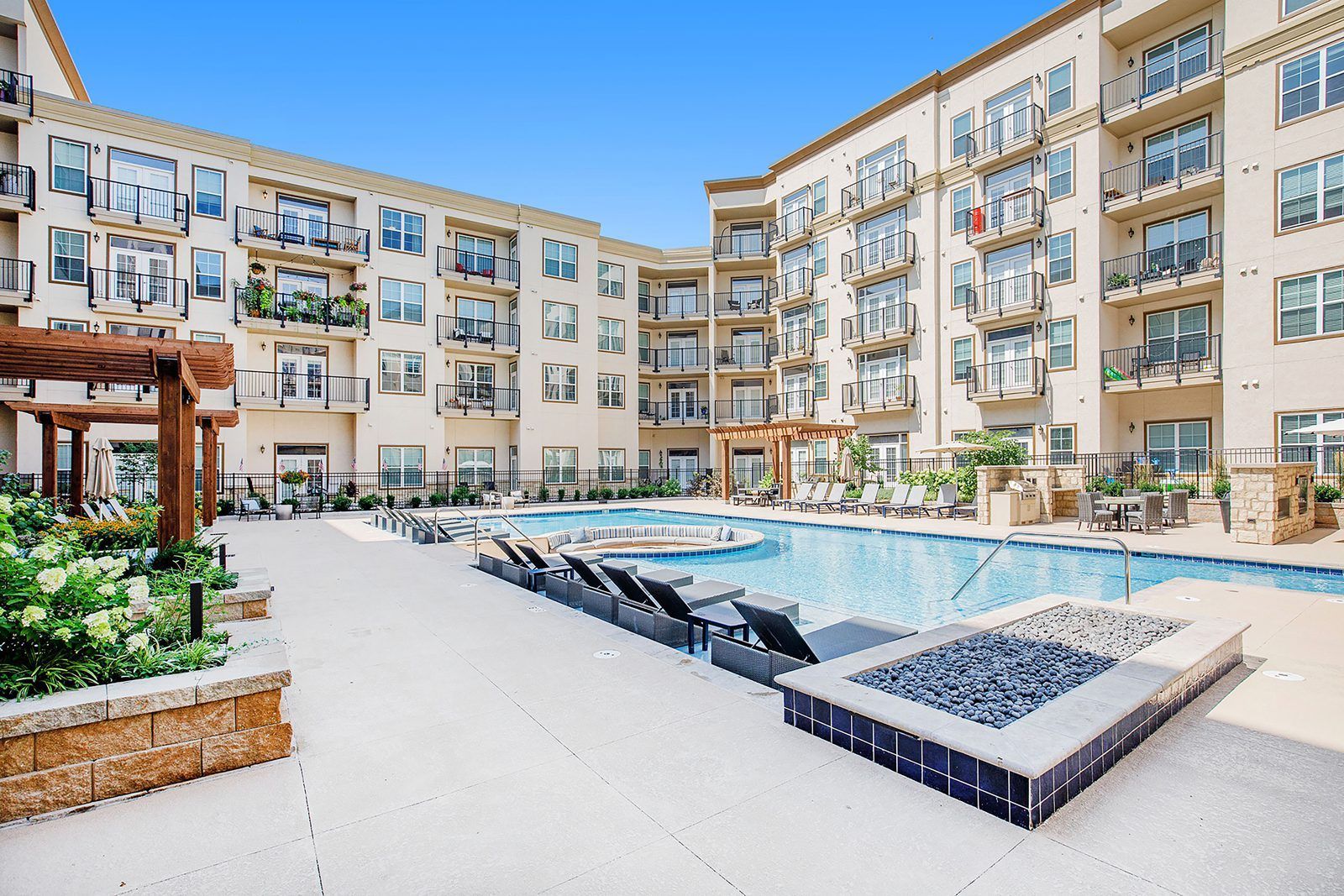 A large apartment building with a swimming pool and a fire pit in front of it.
