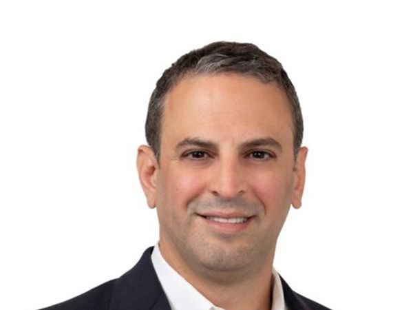 A man in a suit and white shirt is smiling for the camera.
