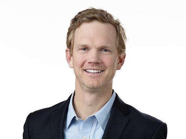A man in a suit and blue shirt is smiling for the camera.