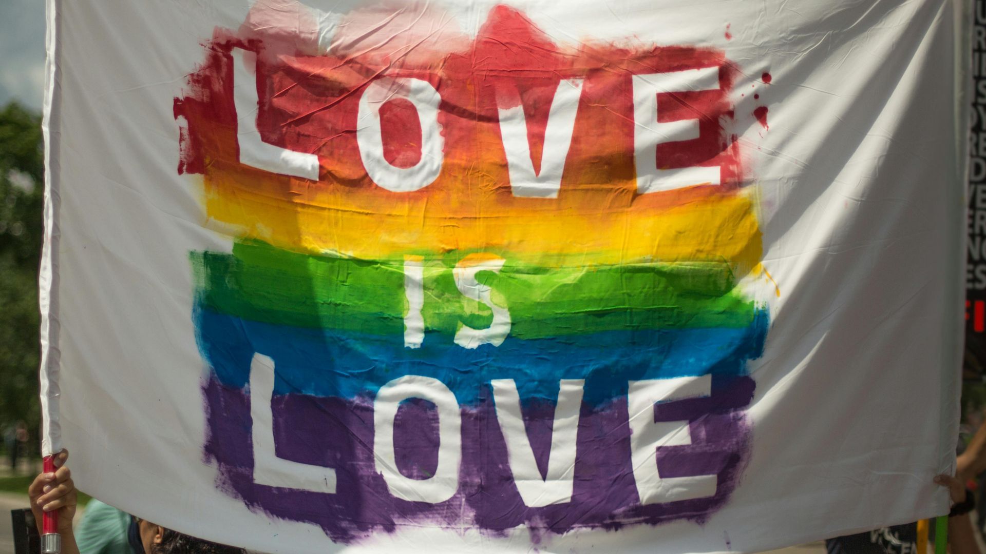 A rainbow flag with the words `` love is love '' painted on it.