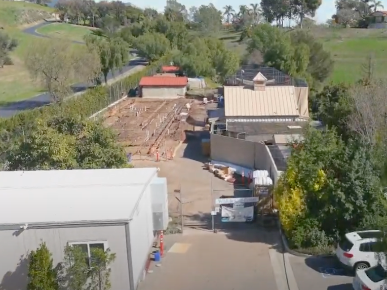 An aerial view of a building under construction with cars parked in front of it