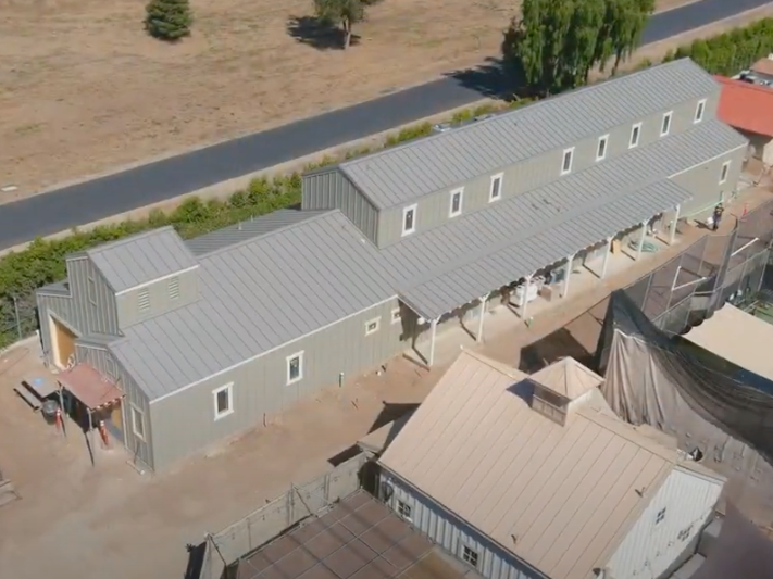 An aerial view of a large building with a gray roof