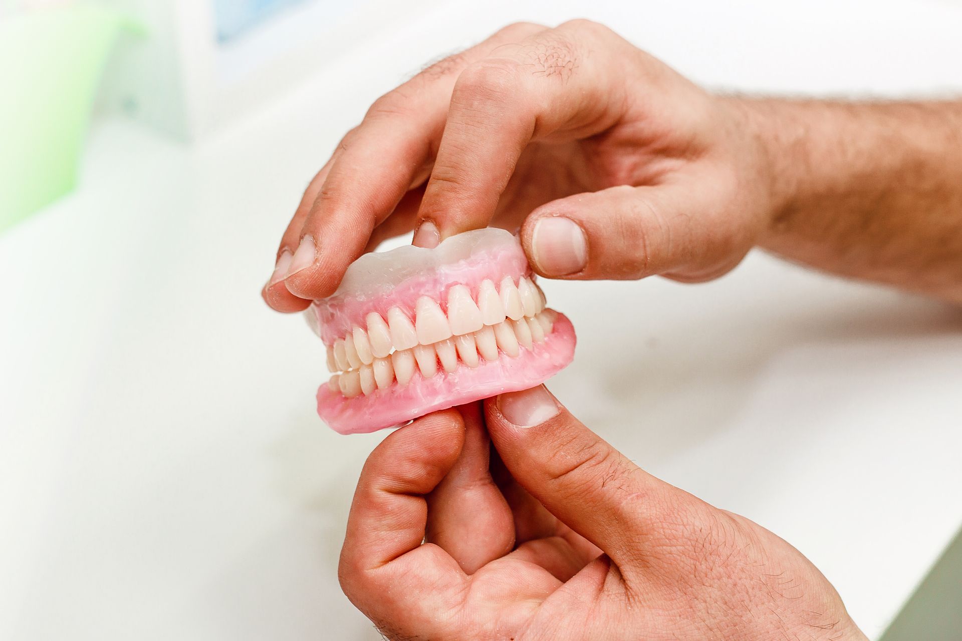 Hands holding a pink dental model with teeth on a white surface Hands holding a pink dental model with teeth on a white surface