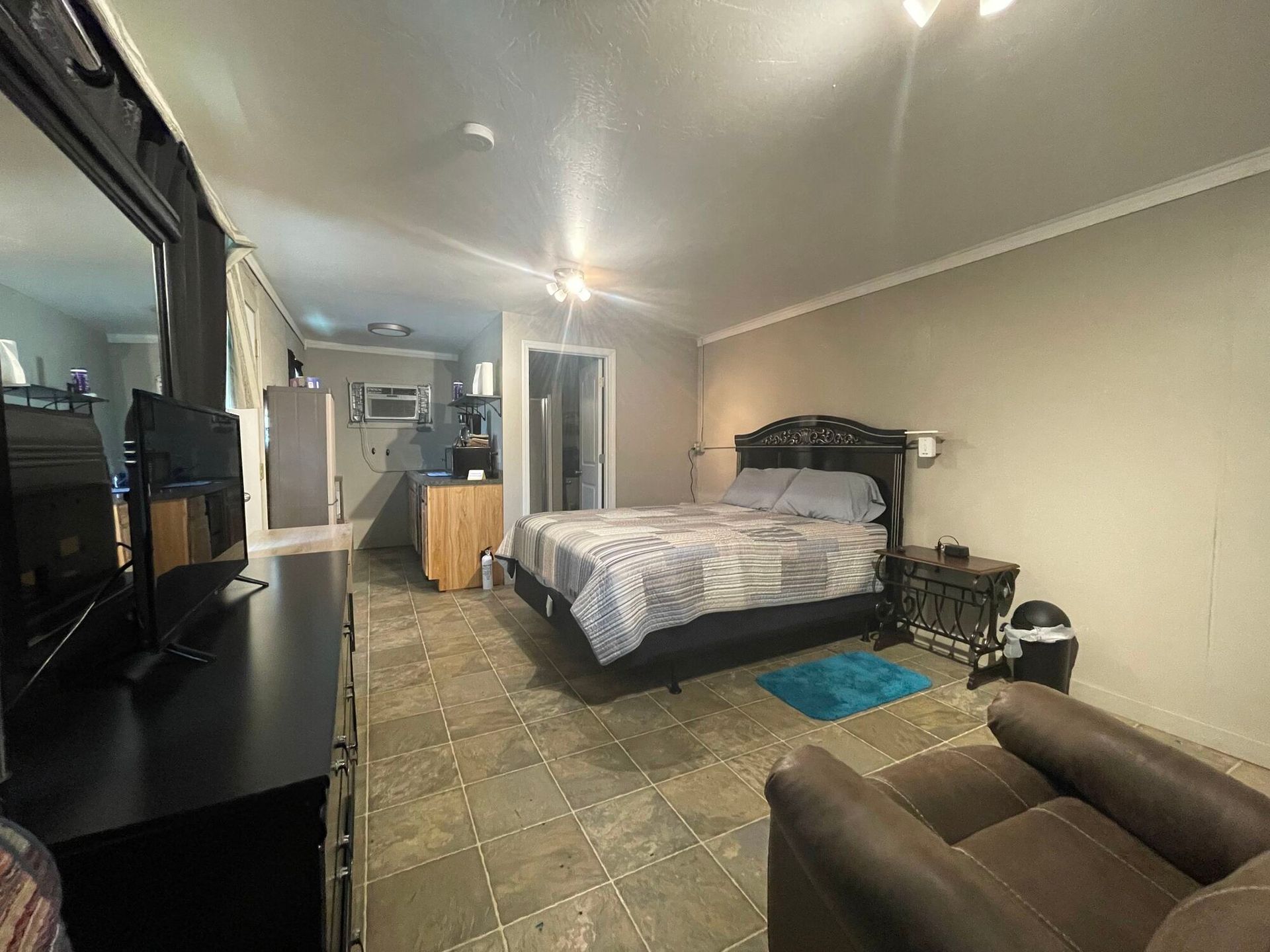 Bedroom with a bed, couch, desk, and TV on tiled floor in a small apartment-style room
