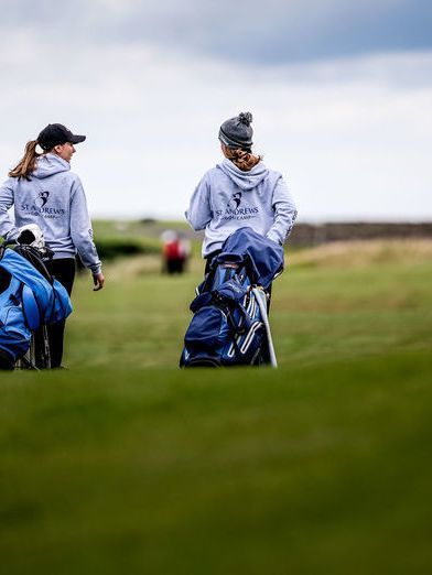 Girls carrying golf bags