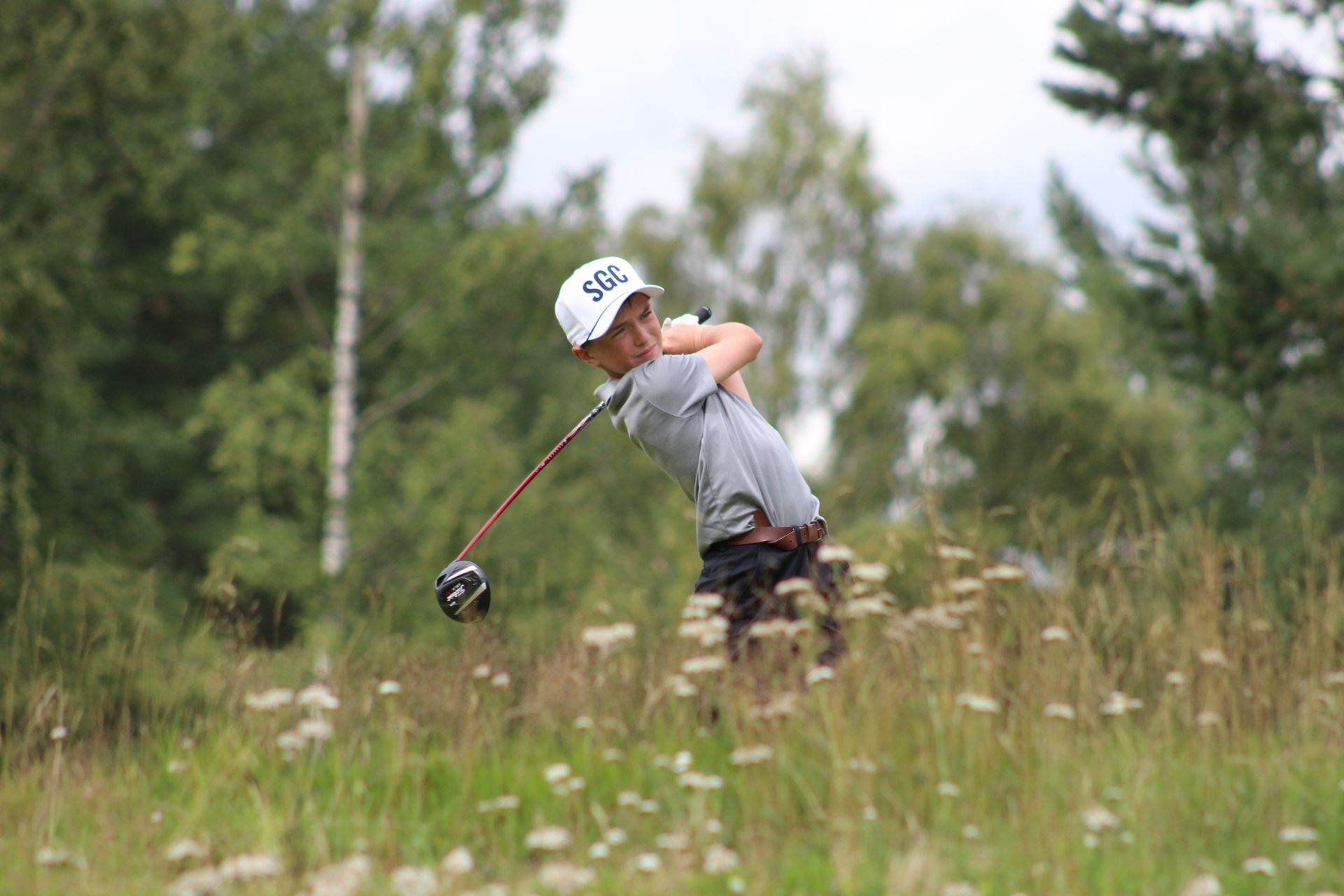 Boy golf swing in the rough