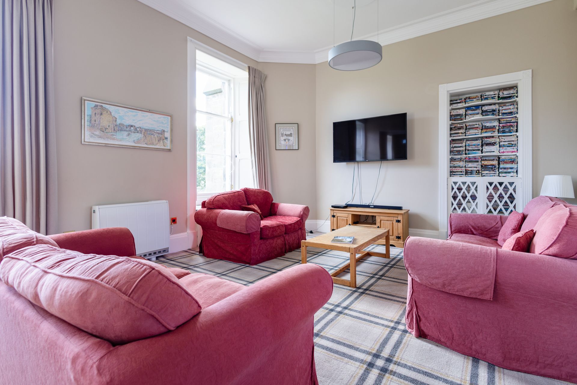 Bright hallway with plaid carpet, white shelves, and a wicker chair beside a wooden sideboard.
