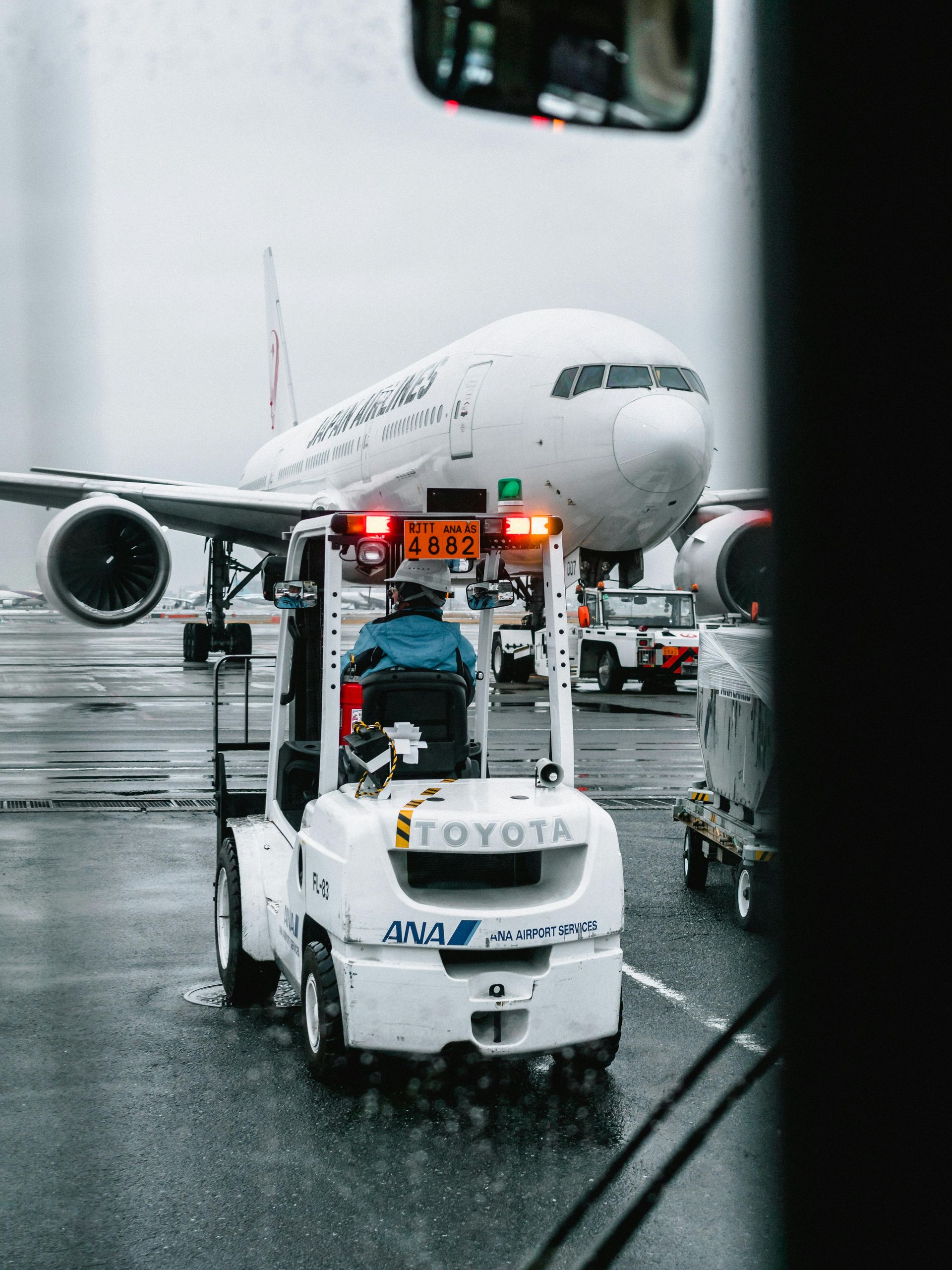Airport tug towing a white airplane on a wet tarmac in the rain