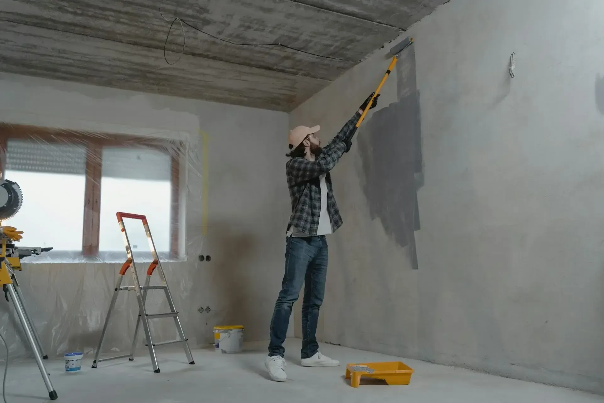 A man is painting a wall with a paint roller.