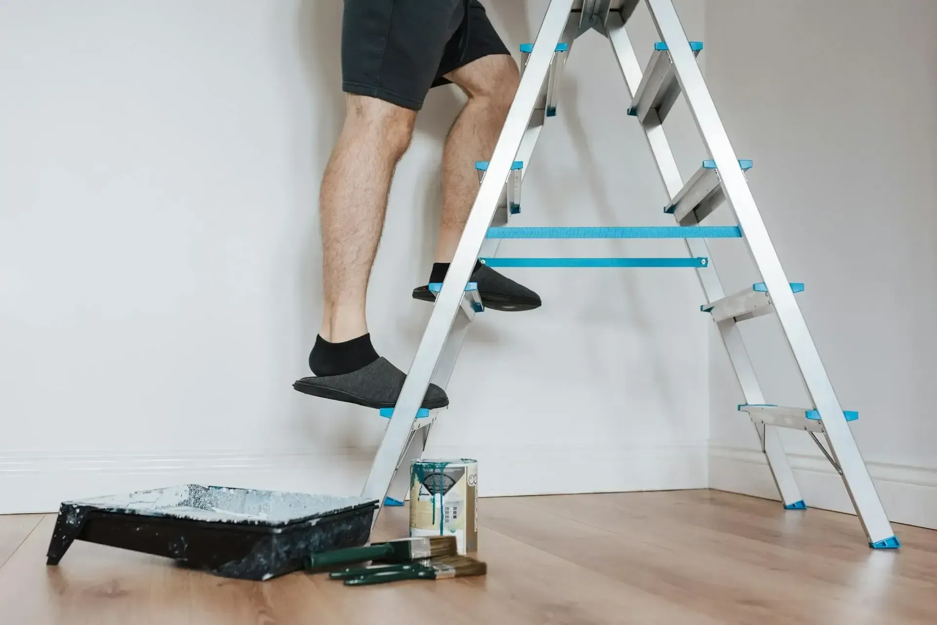 A man is climbing a ladder to paint a wall.