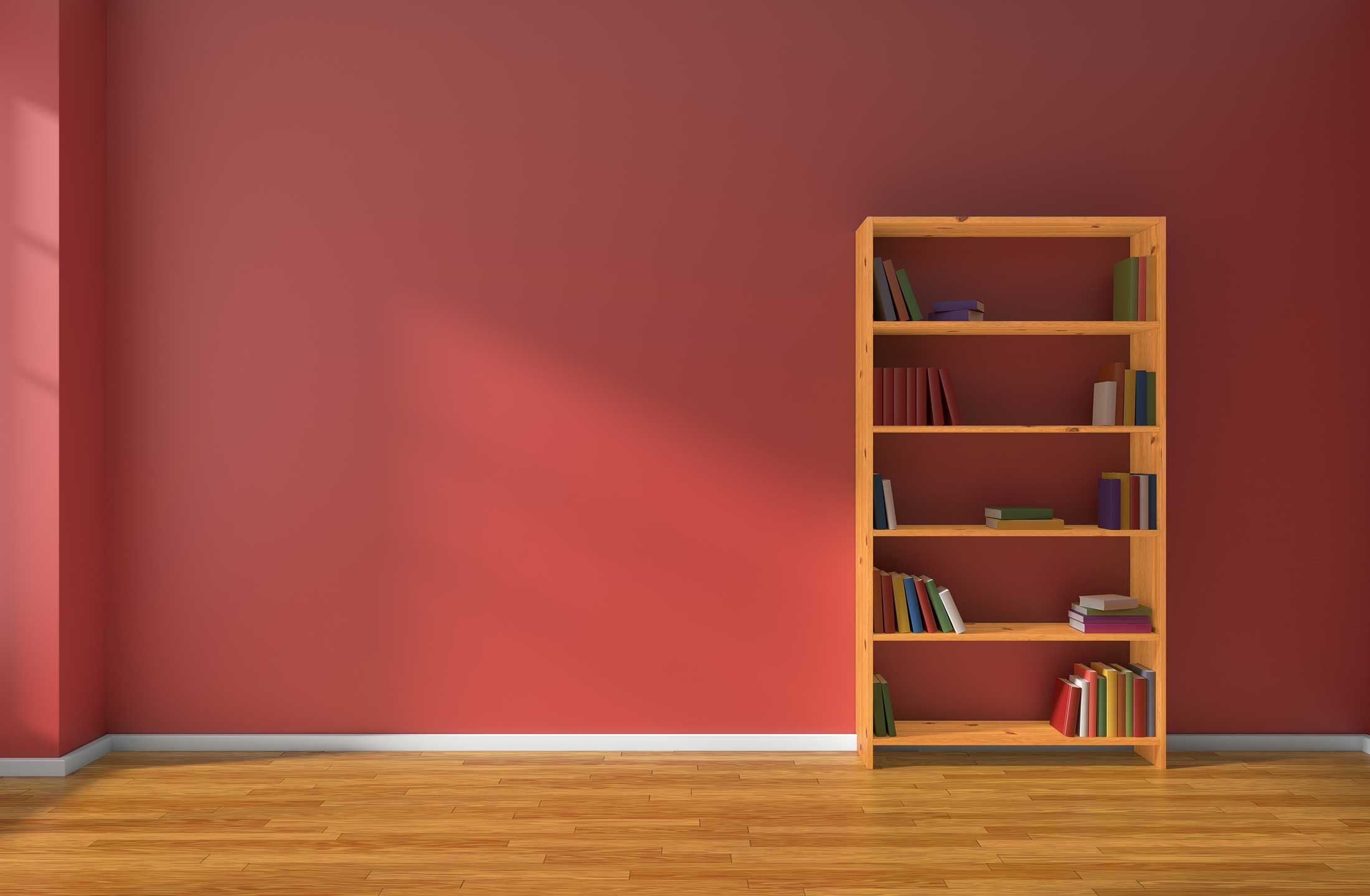 An empty room with red walls and a wooden bookshelf.