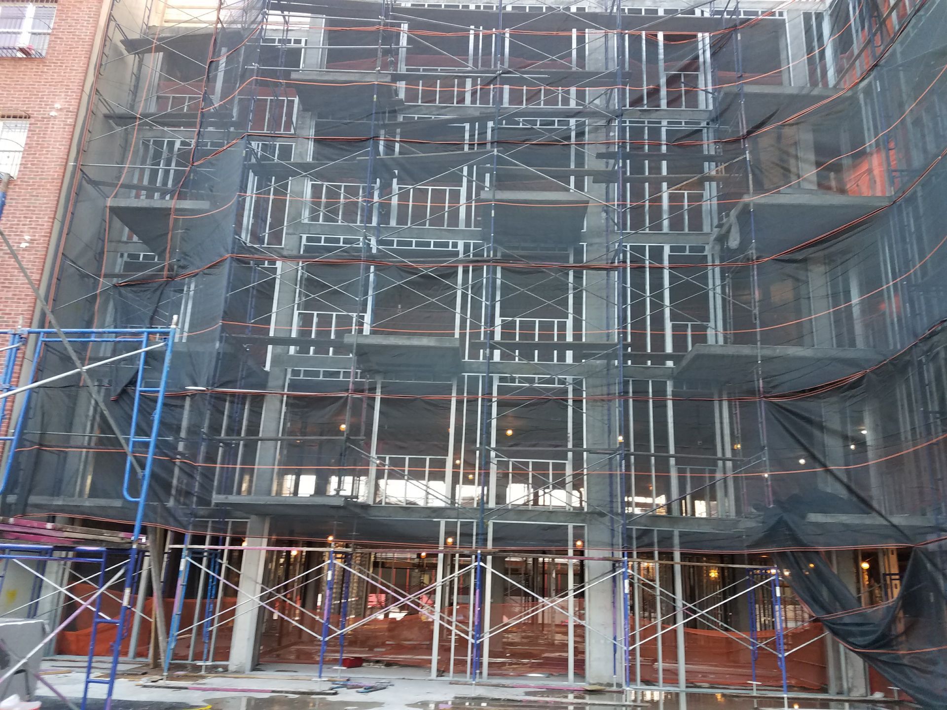 Building under construction, scaffolding, protective netting, open window frames.
