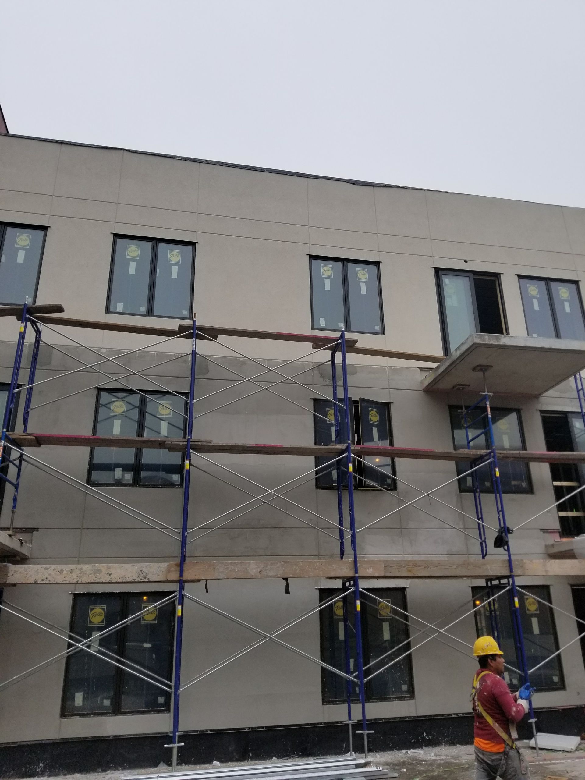 Building under construction with scaffolding and a worker wearing a hard hat.