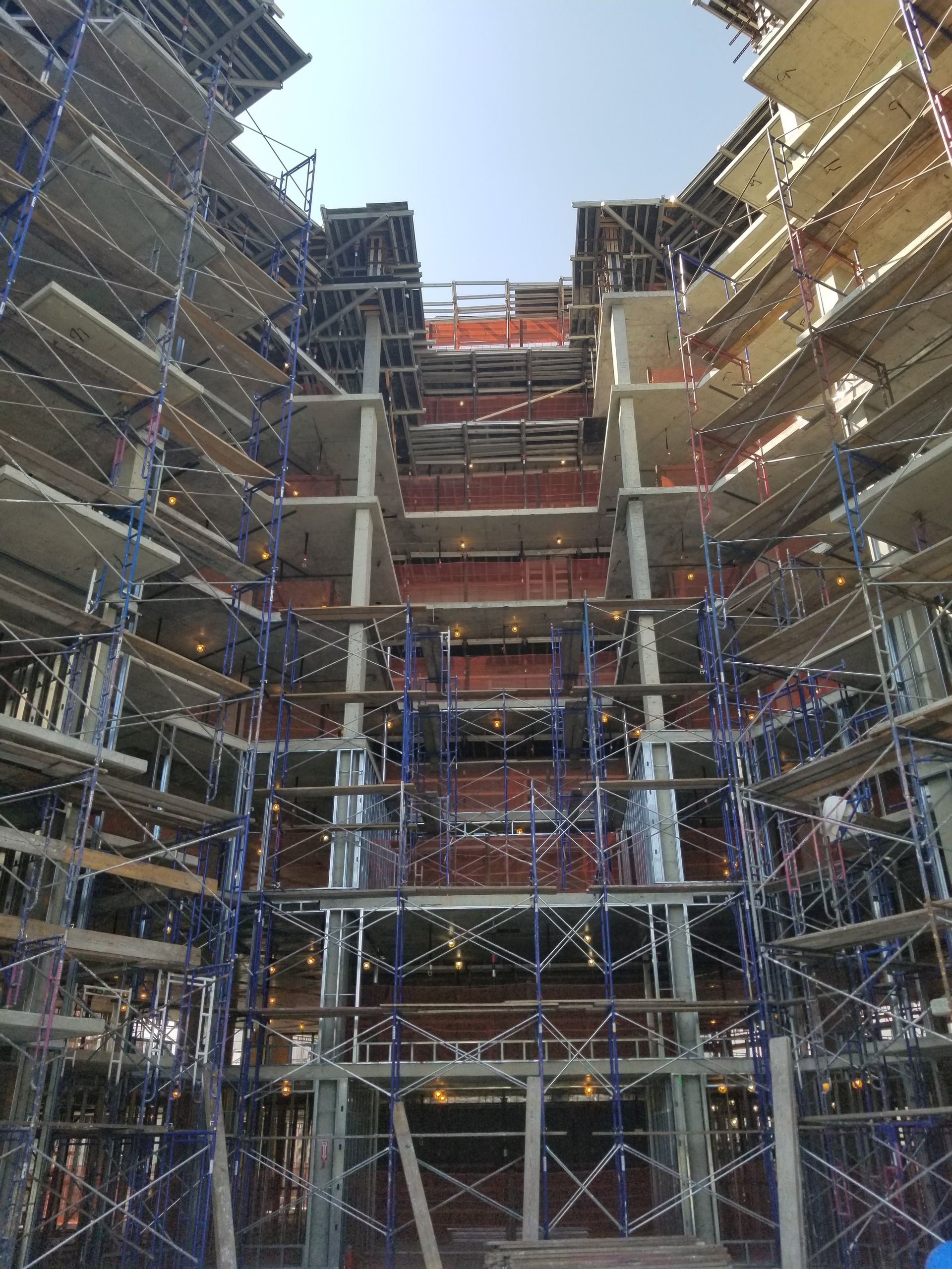Building under construction, with scaffolding surrounding the structure. Red brick and concrete are visible.