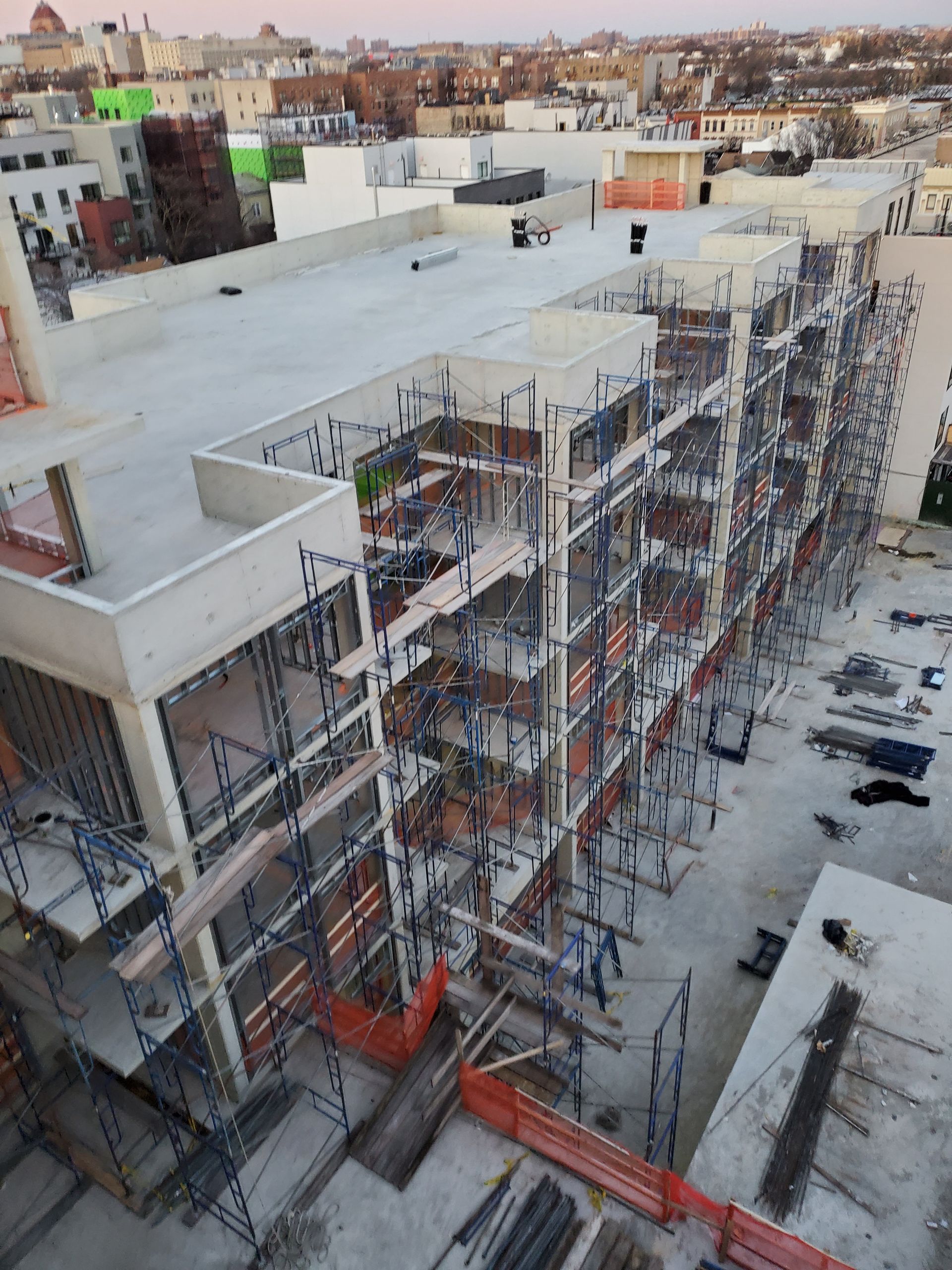 Construction site of a multi-story building, scaffolding and concrete work visible, with a cityscape background.