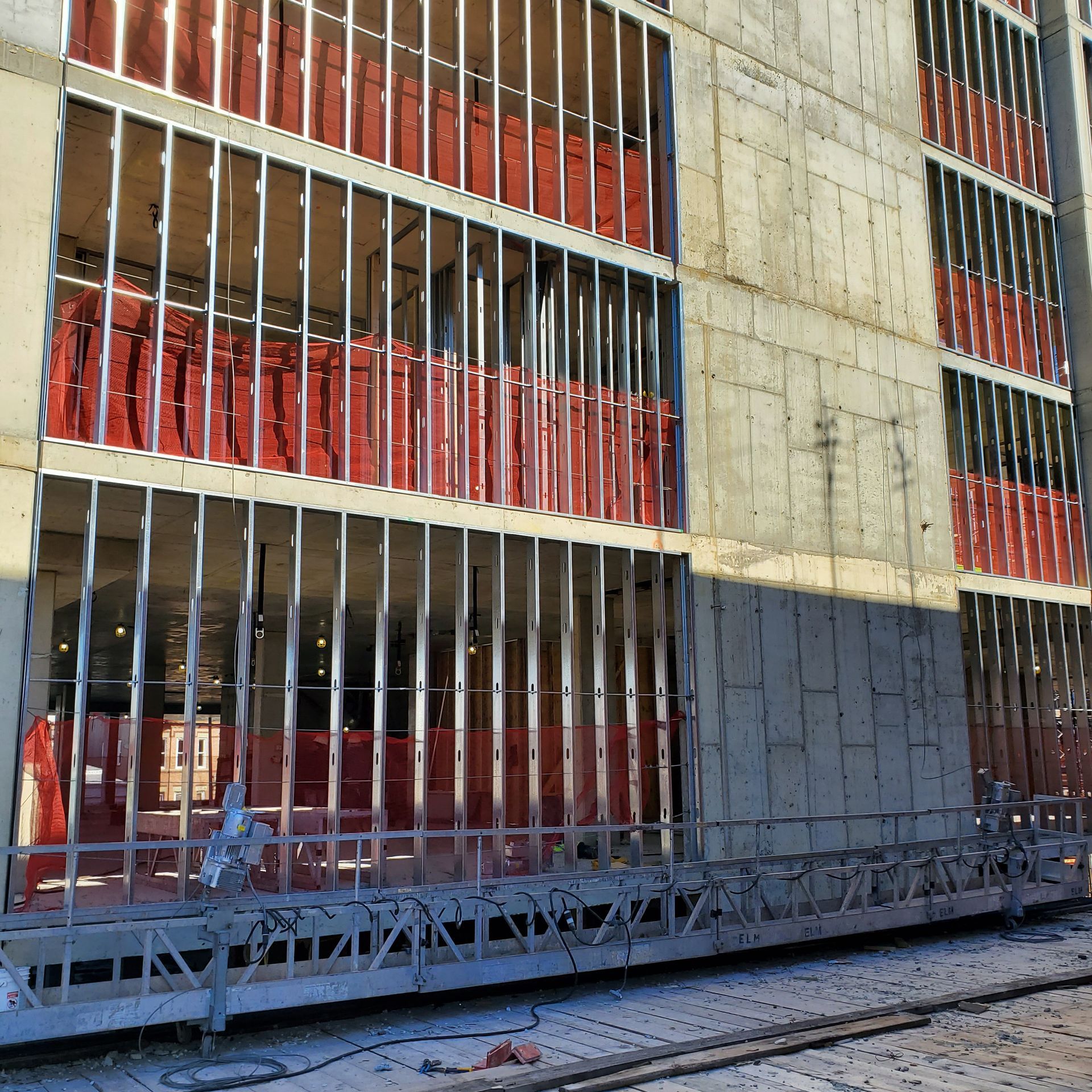 Construction of a building exterior with metal framing and red insulation visible.