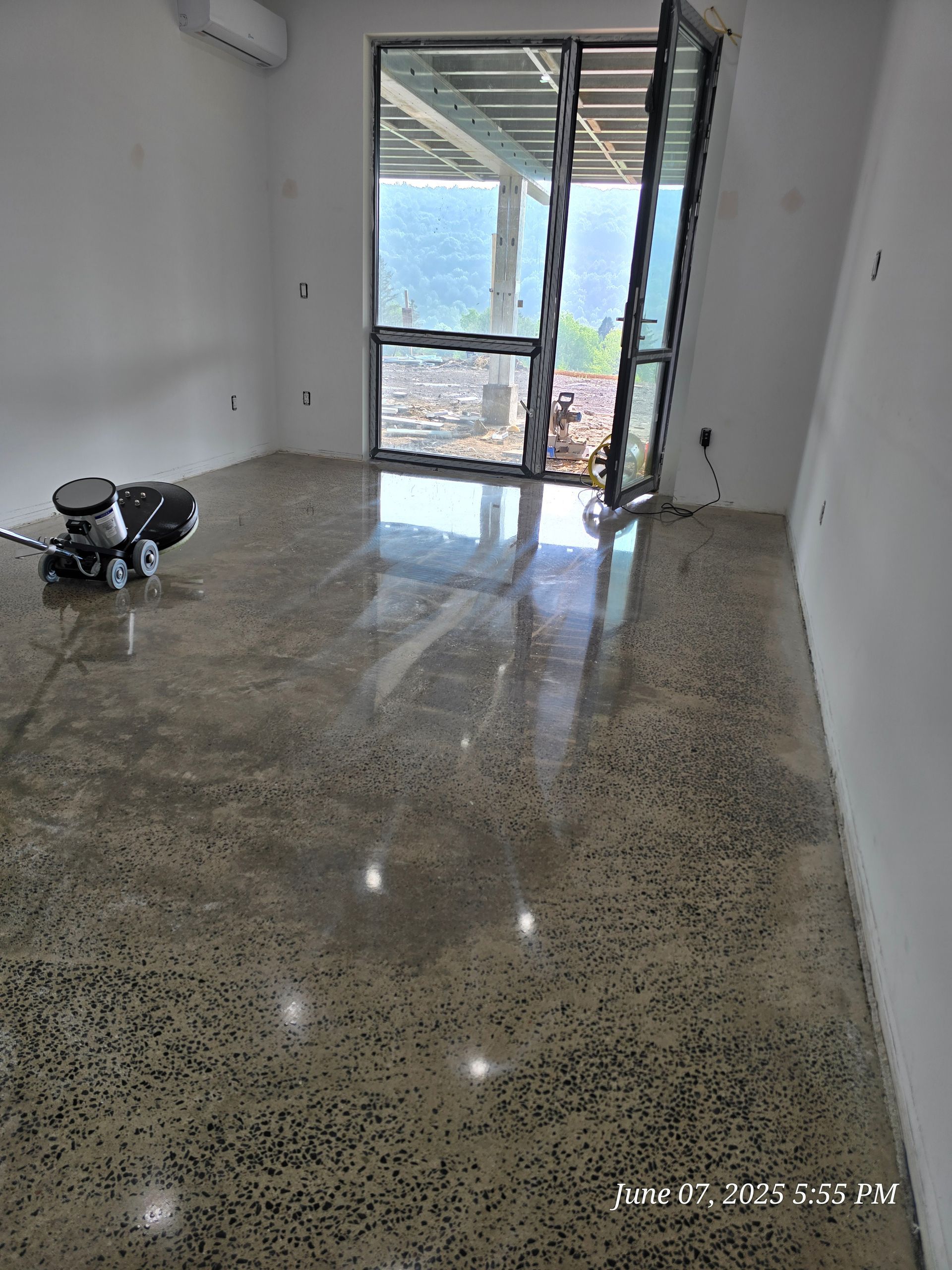 Room with polished concrete floor, open glass doors, and a floor grinder.