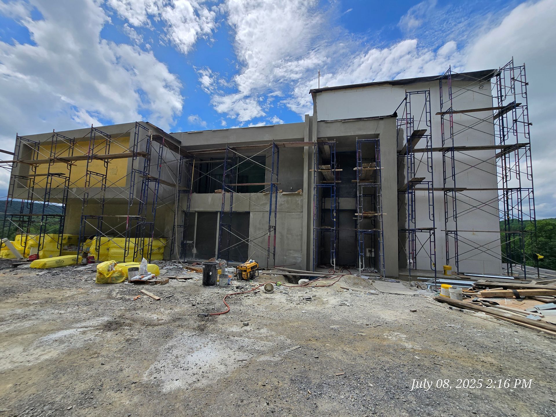 Building under construction with scaffolding, cloudy sky background.