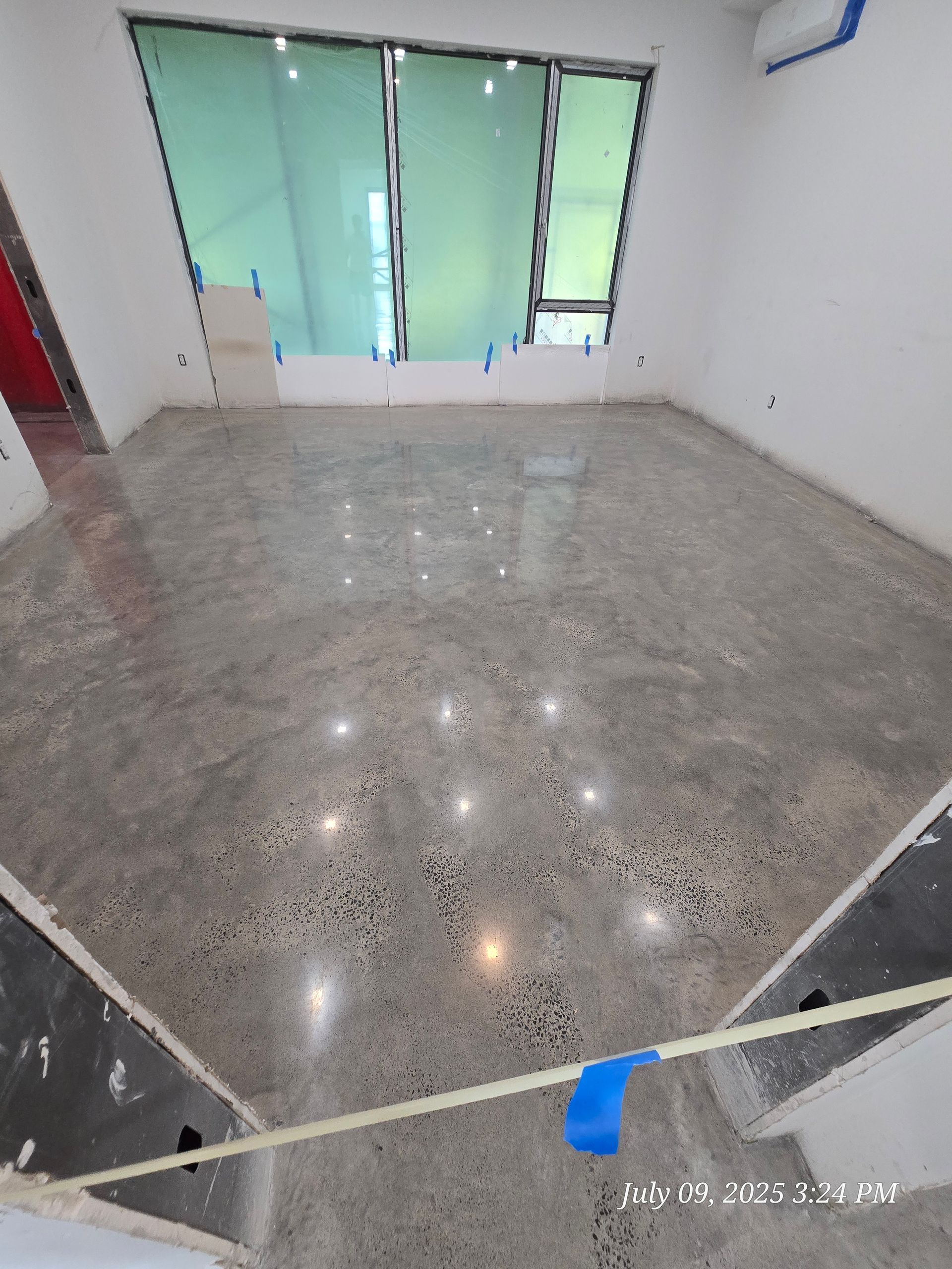 Empty room with polished concrete floor, large windows, and white walls.