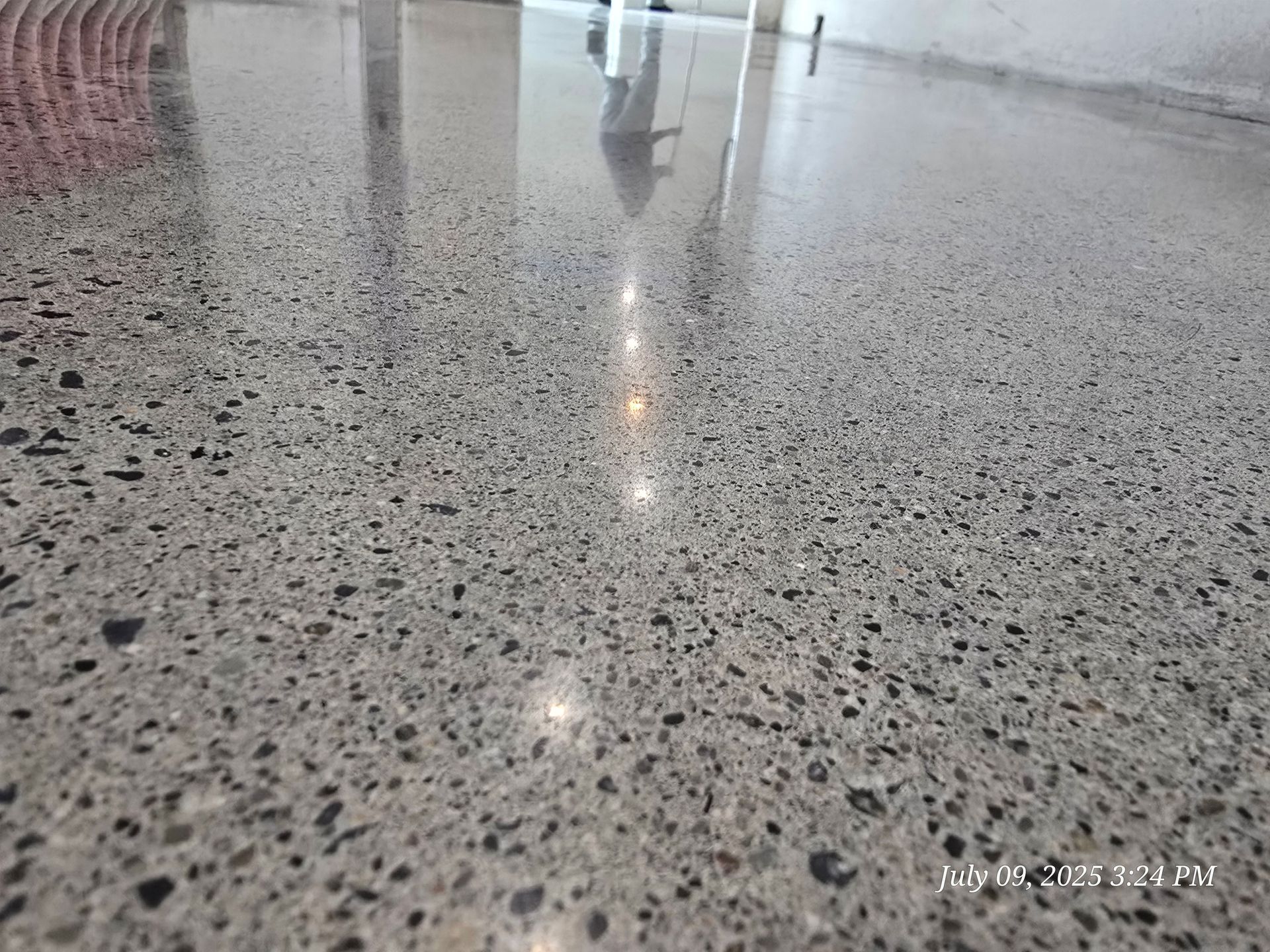 Polished gray concrete floor with exposed aggregate reflecting light.