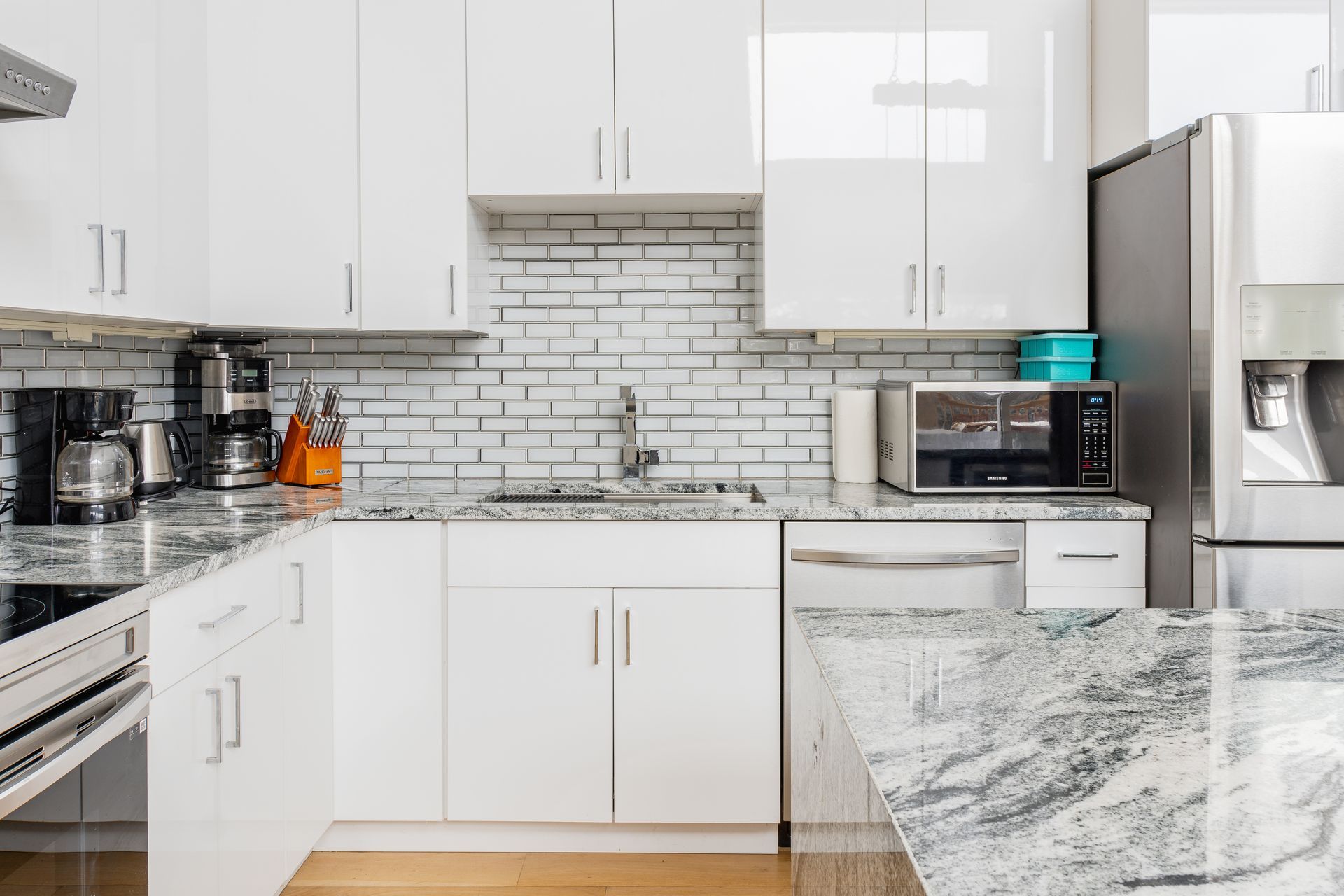 White kitchen with granite countertops, white cabinets, and stainless steel appliances.