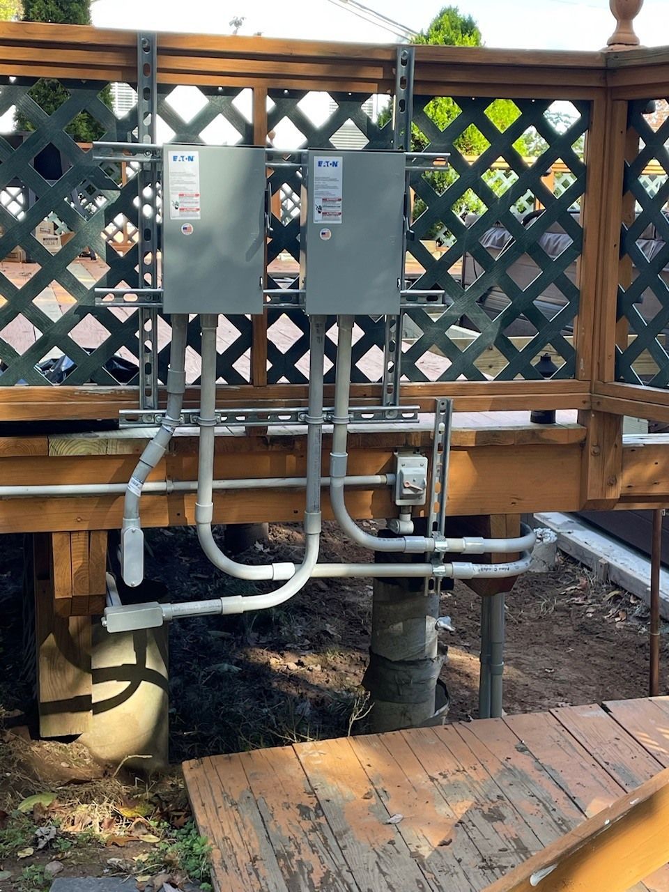 A wooden deck with a fence and electrical boxes on it
