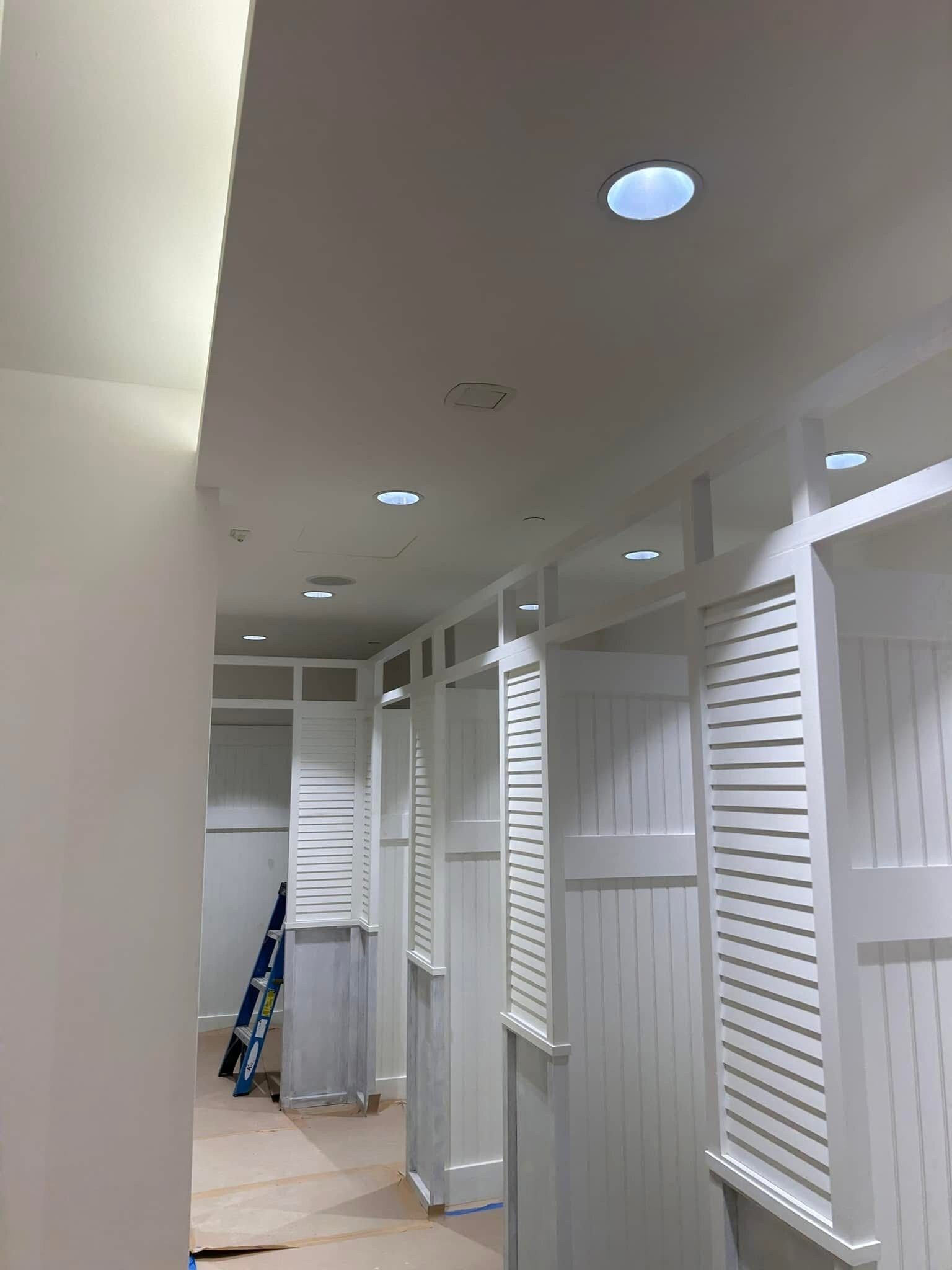 A hallway with white cabinets and a ladder in the corner.