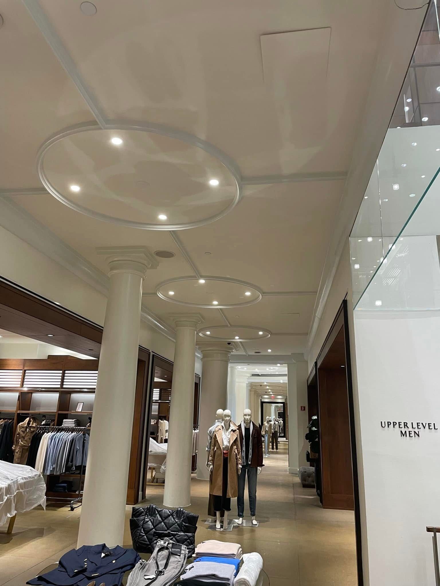 A long hallway in a clothing store with mannequins and clothes on display.