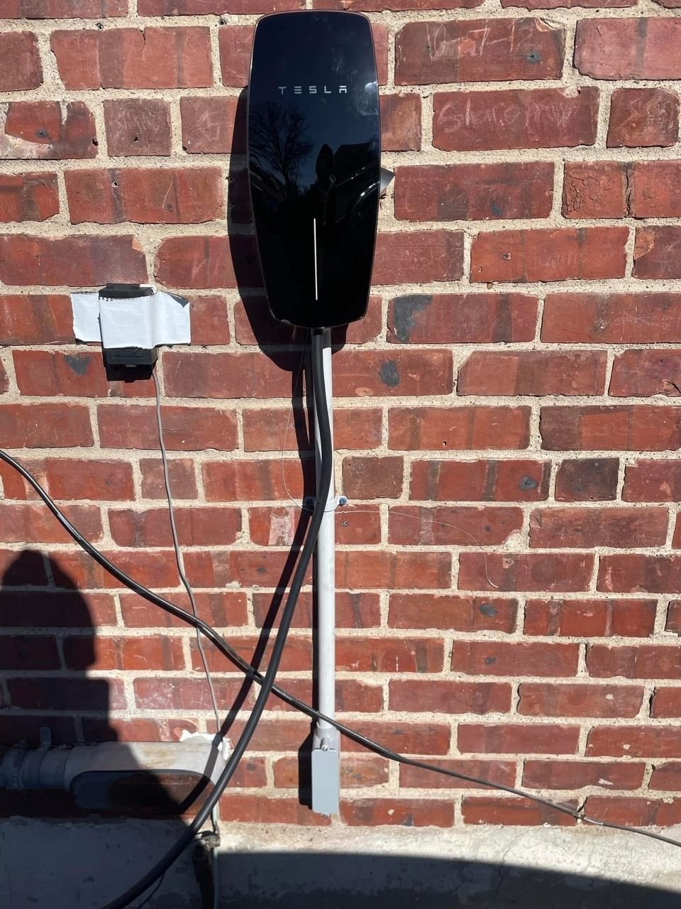A tesla charging station is attached to a brick wall