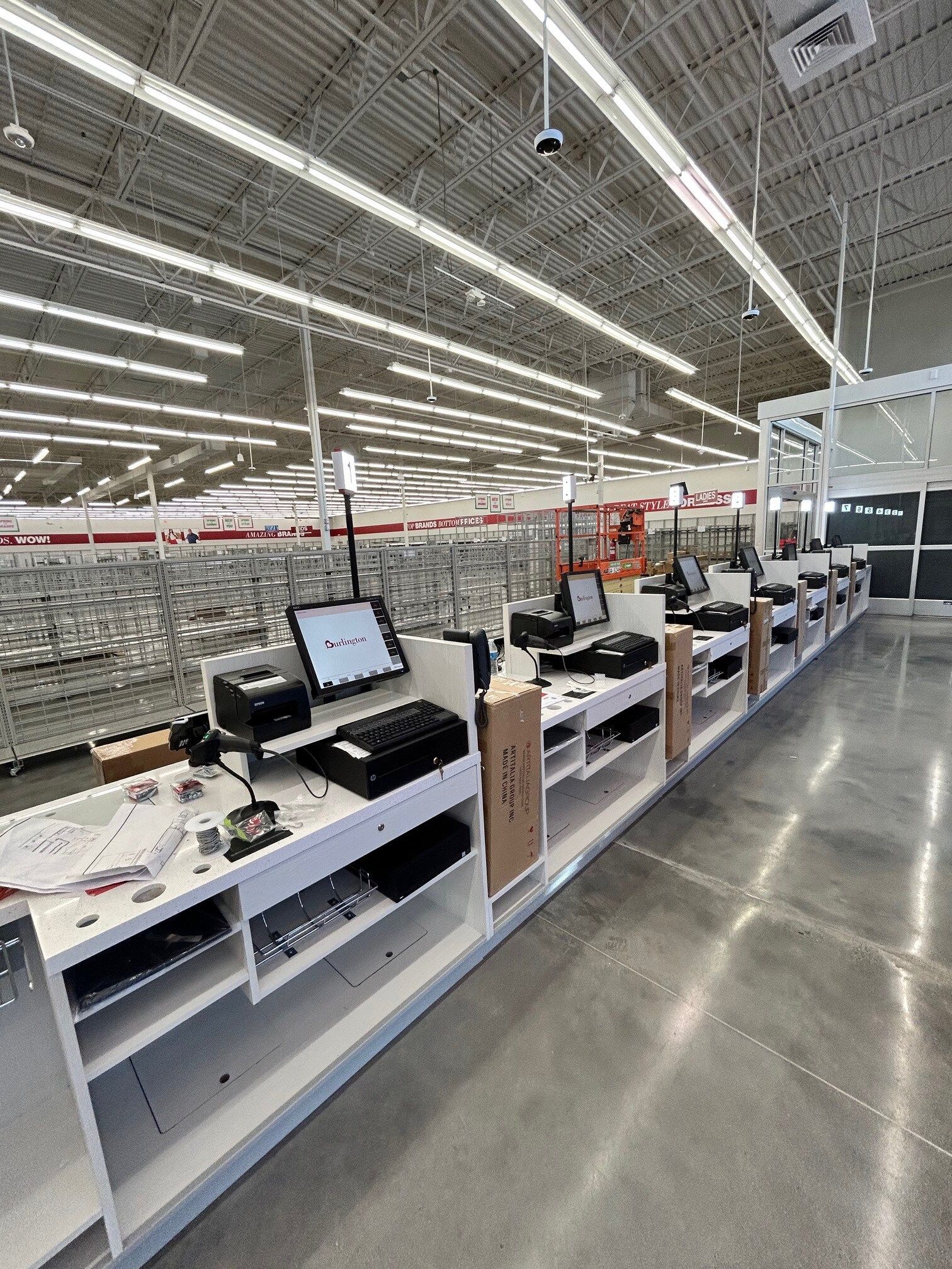 A row of cash registers in a store with computers on them.