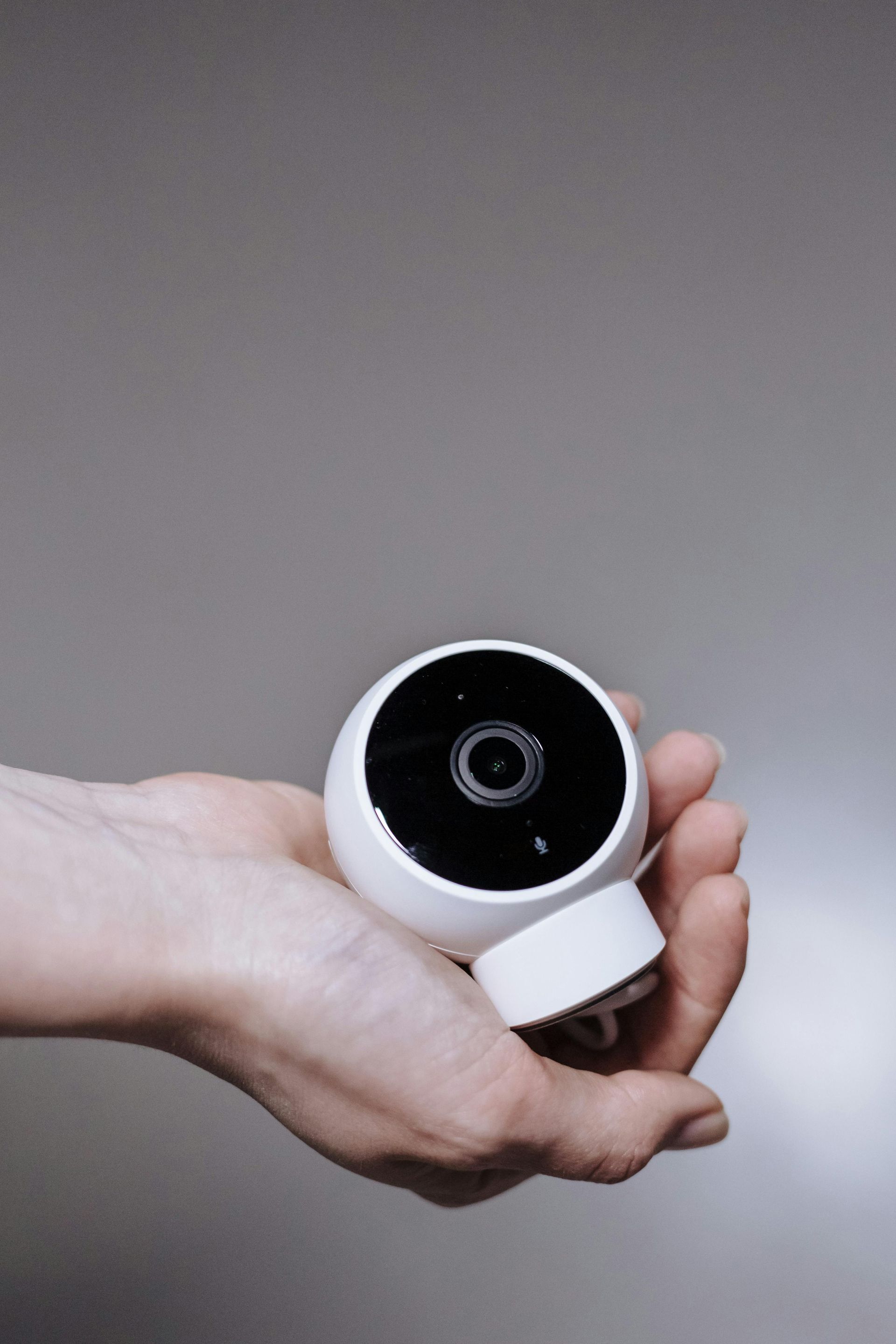 A person is holding a small white camera in their hand.