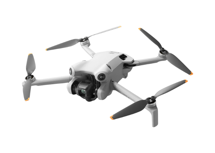 A white DJI Mini 4 Pro drone with a camera attached to it is flying on a white background.