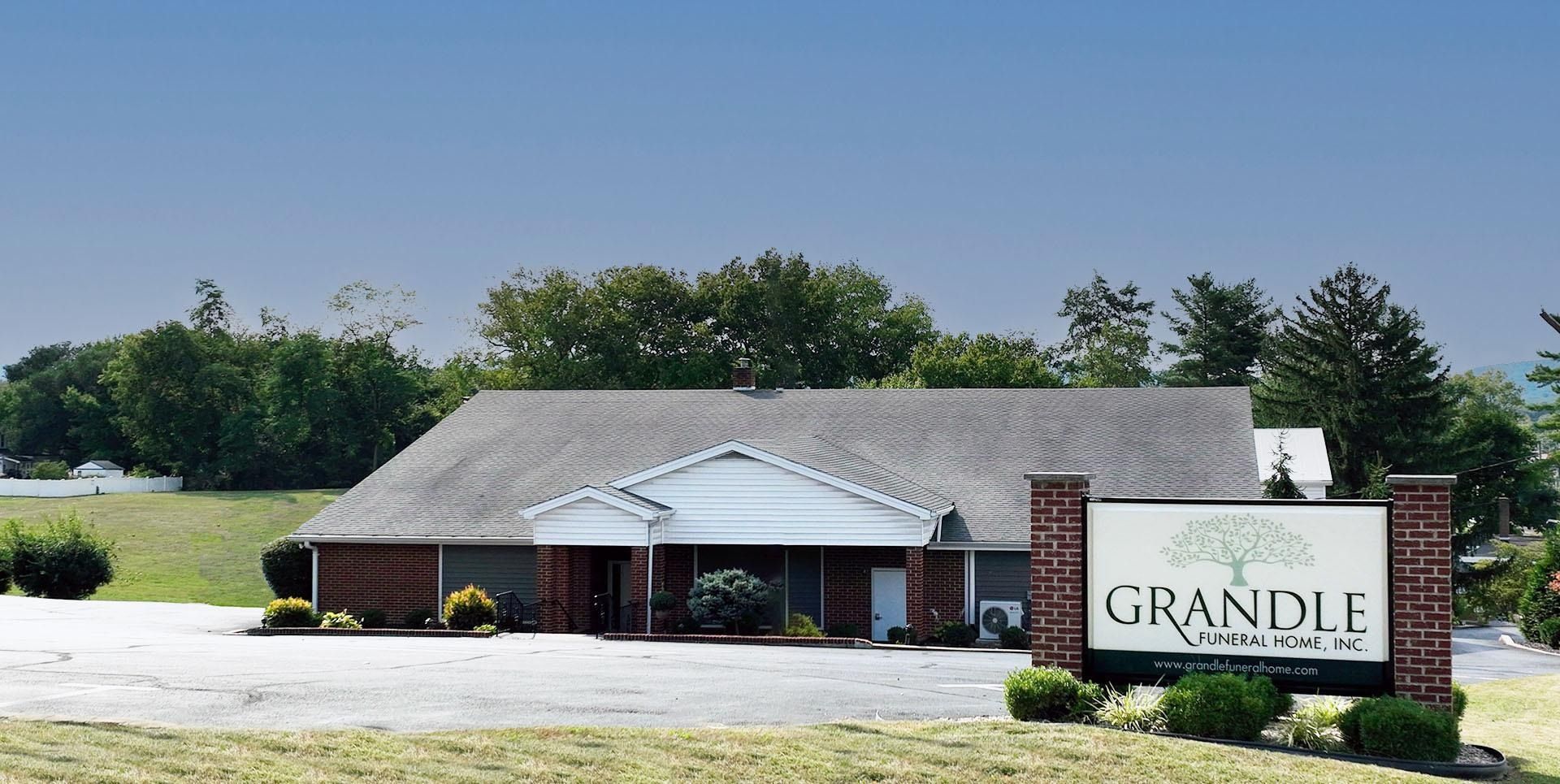 Grandle funeral home building with a brick sign and landscaped lawn under a gray sky